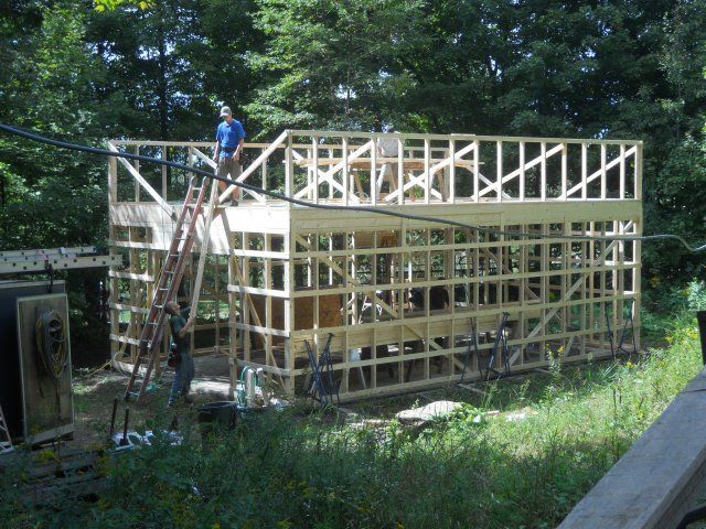 A man on a ladder stands on top of a wooden structure
