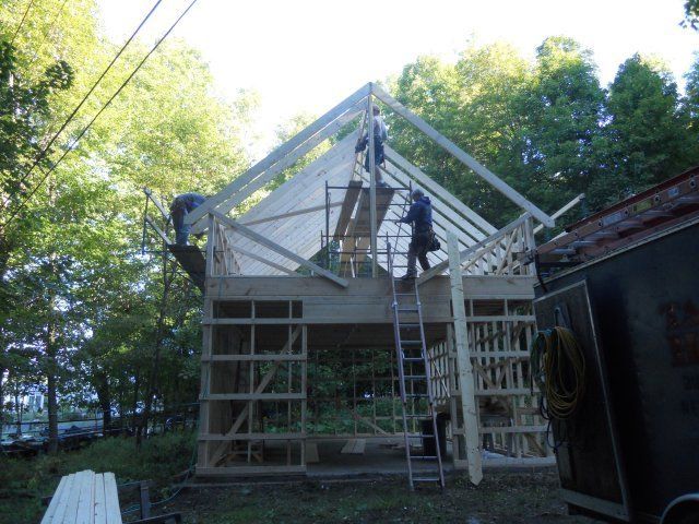 A man on a ladder is working on the roof of a building