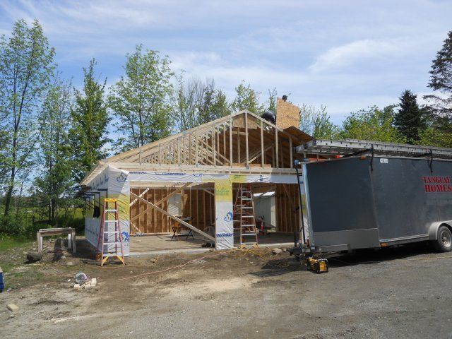 A house is being built and a trailer is parked in front of it