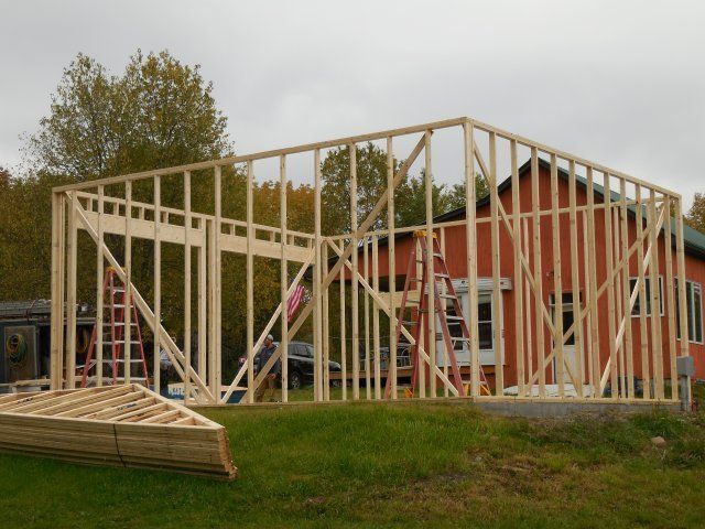 A large wooden structure is being built in front of a red building
