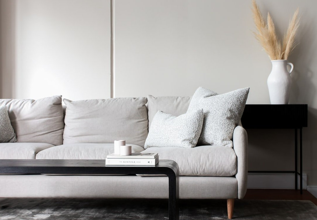 light gray couch with wooden legs and a black coffee table in front