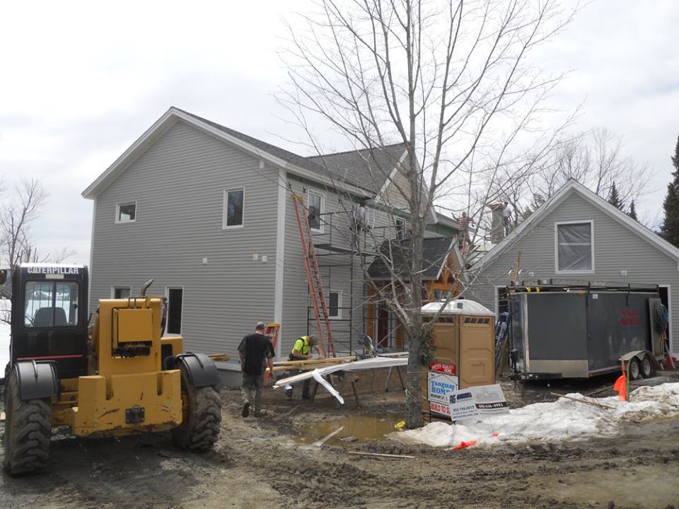 A yellow forklift is parked in front of a house under construction