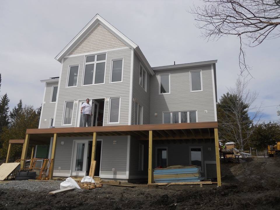 A man stands on the deck of a house under construction