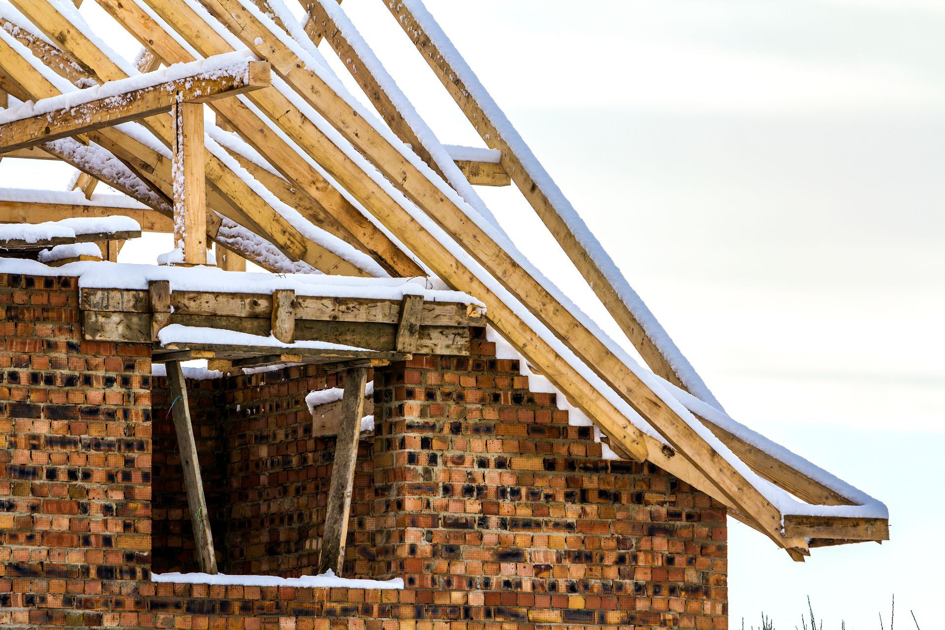 A brick building under construction with snow on the roof 