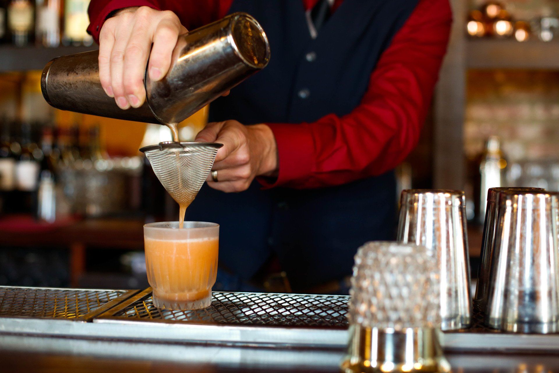bartender at planter's house pouring a cocktail through a strainer