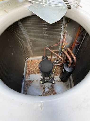 Open rooftop mechanical unit with pipes, cables, and a black compressor inside a circular vent opening