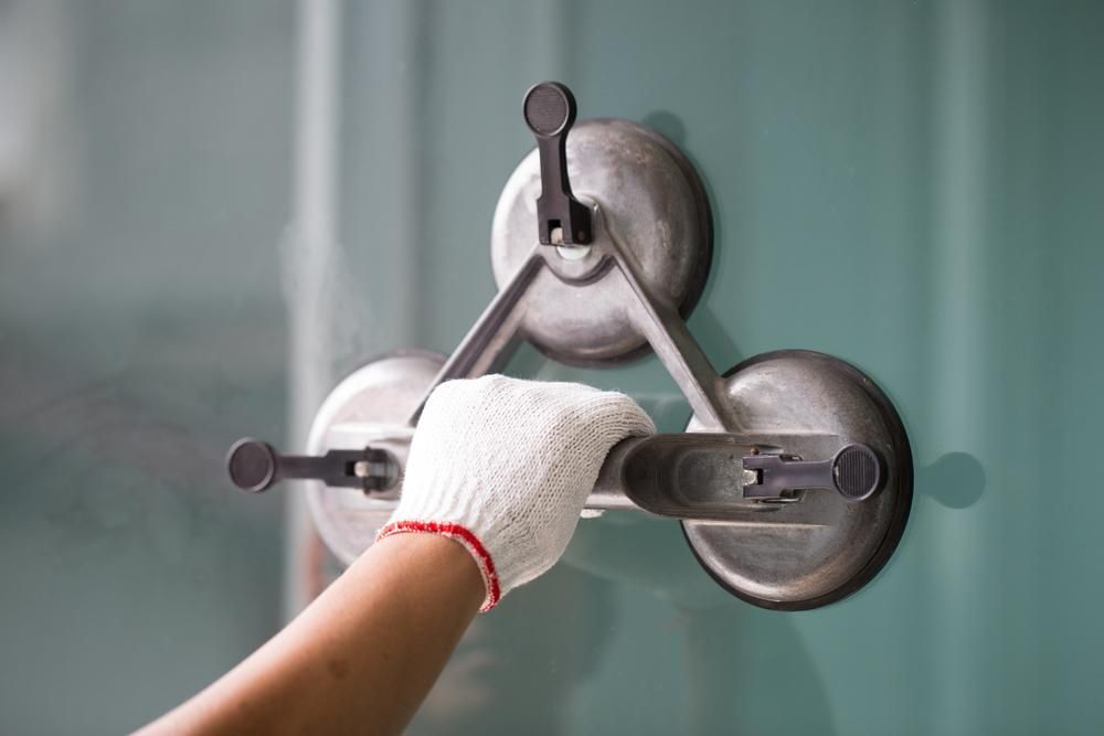 A Person Is Using a Suction Cup to Lift a Glass on A Wall — Grafton Glass in South Grafton, NSW