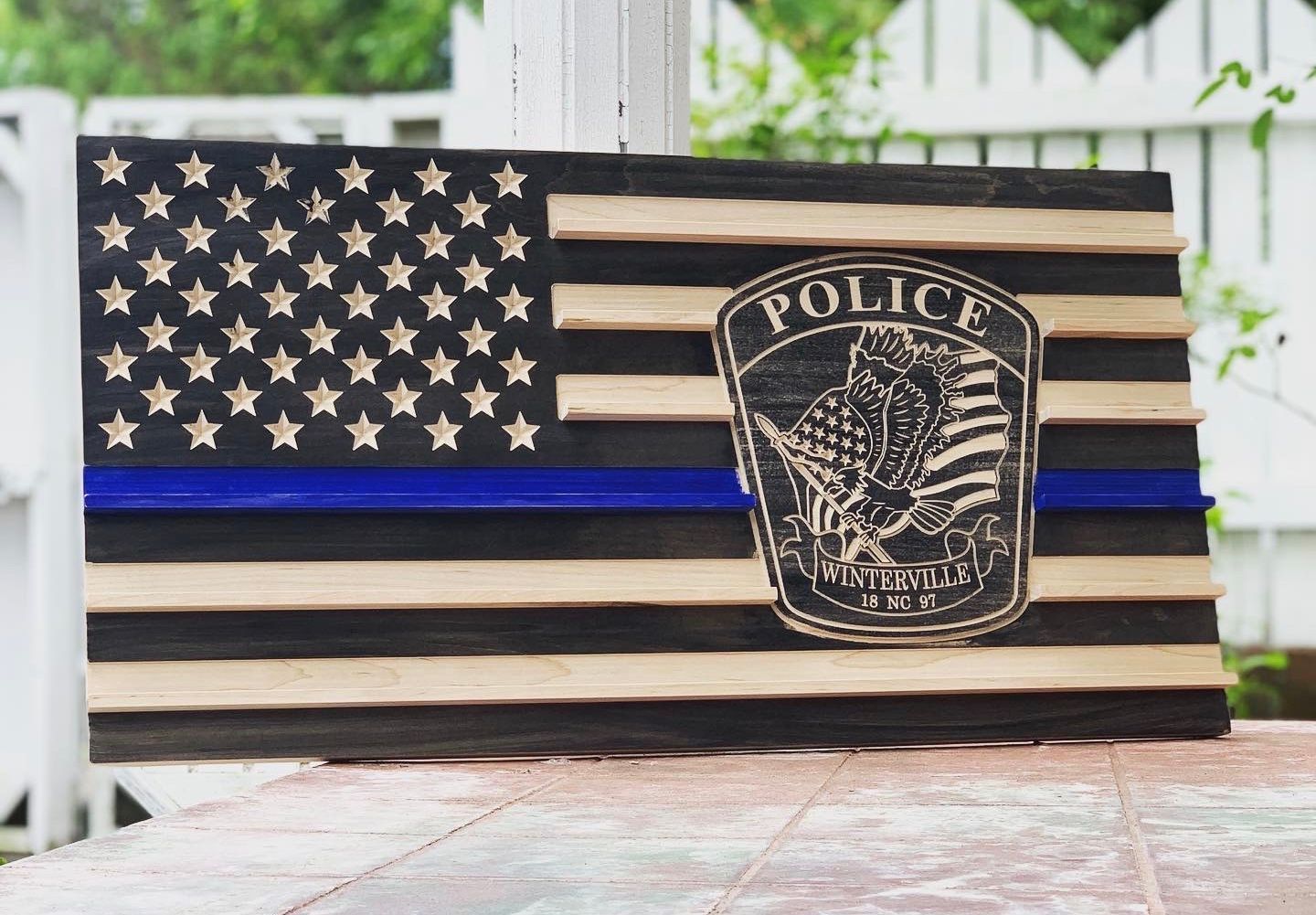 A wooden american flag with a police badge on it