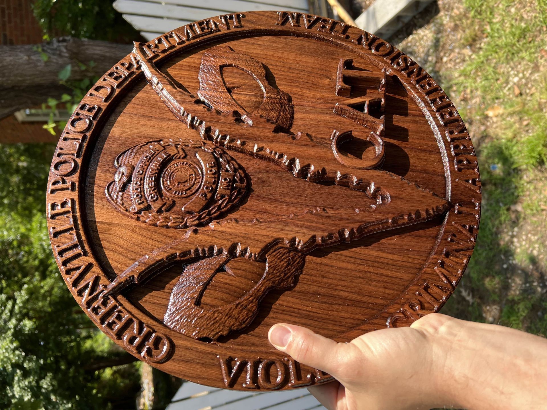 A person is holding a wooden plaque that says ' greenville ' on it