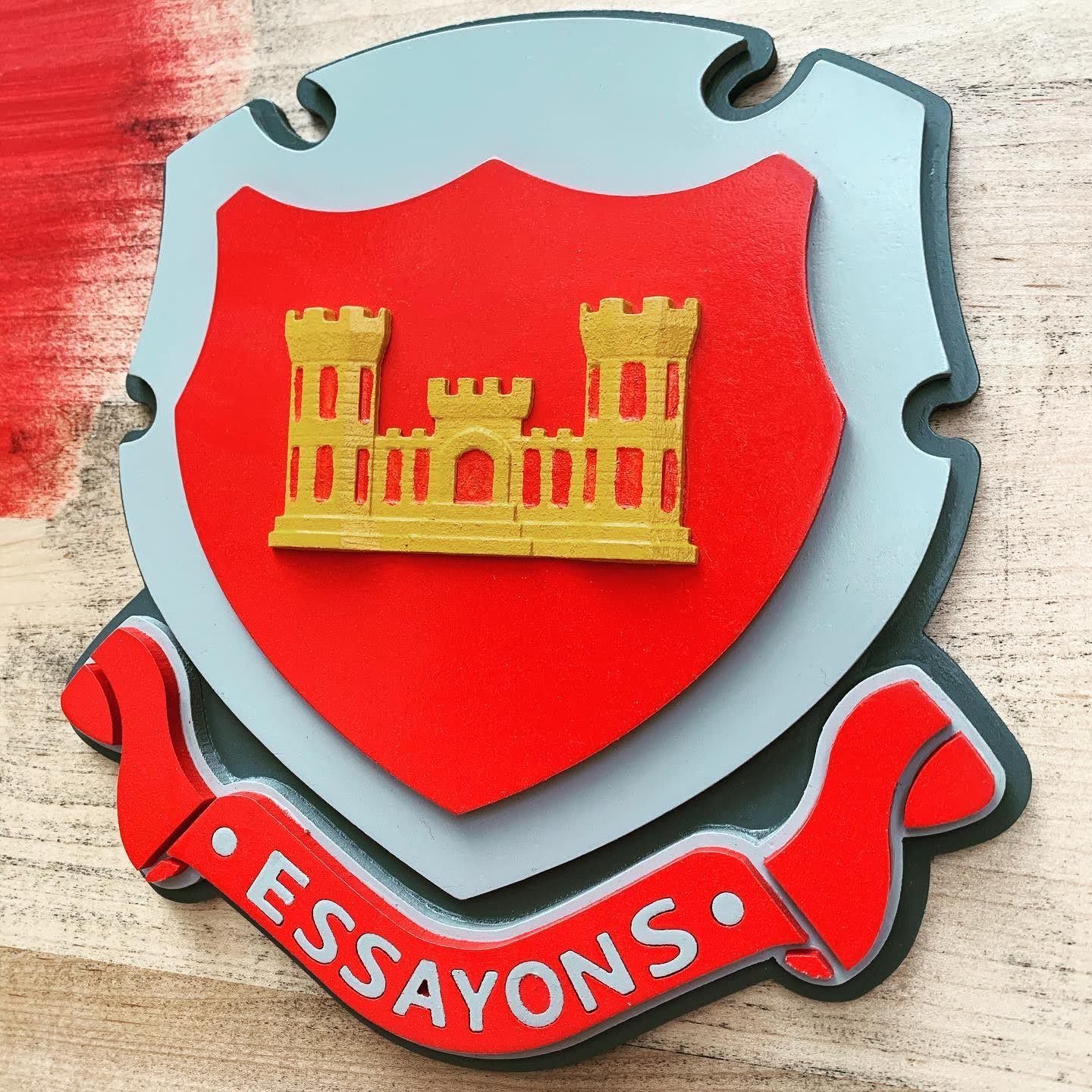A red shield with the words essayons on it