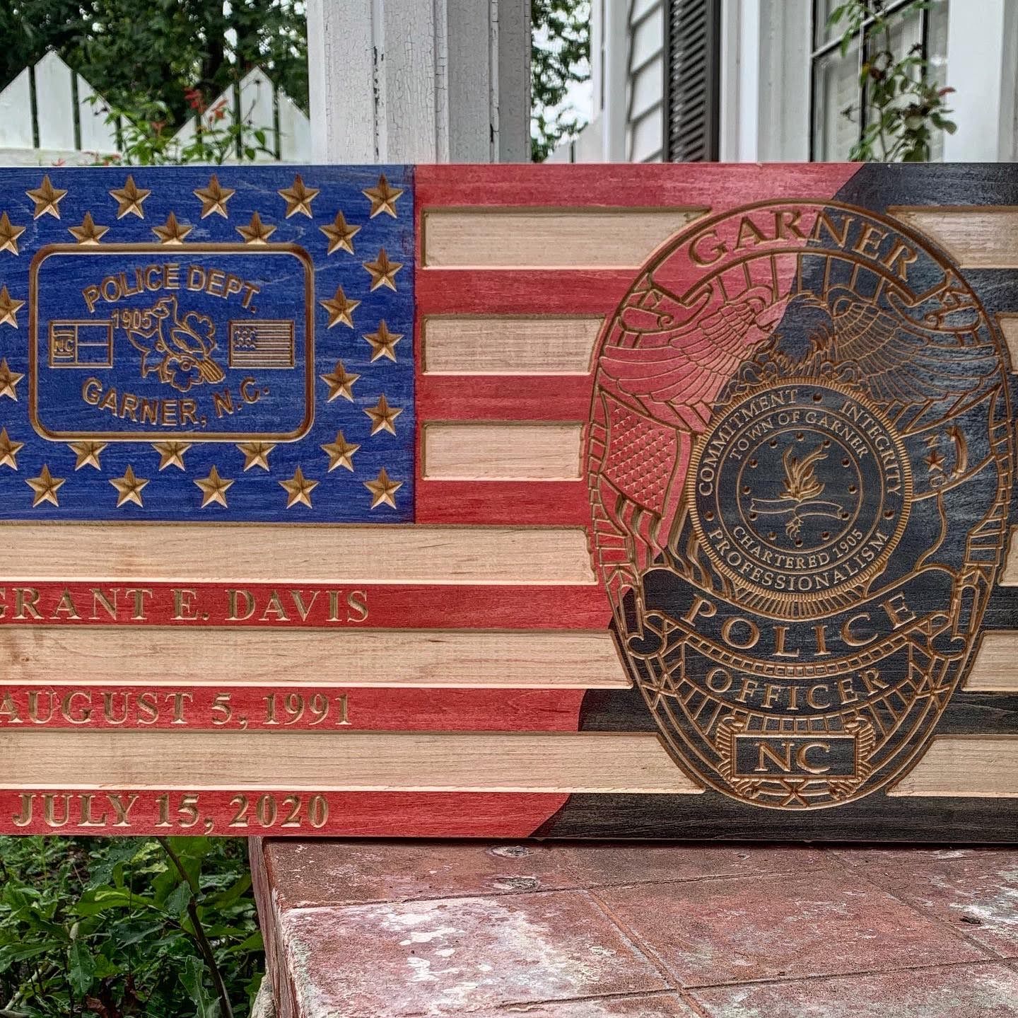A wooden american flag with a police badge on it.