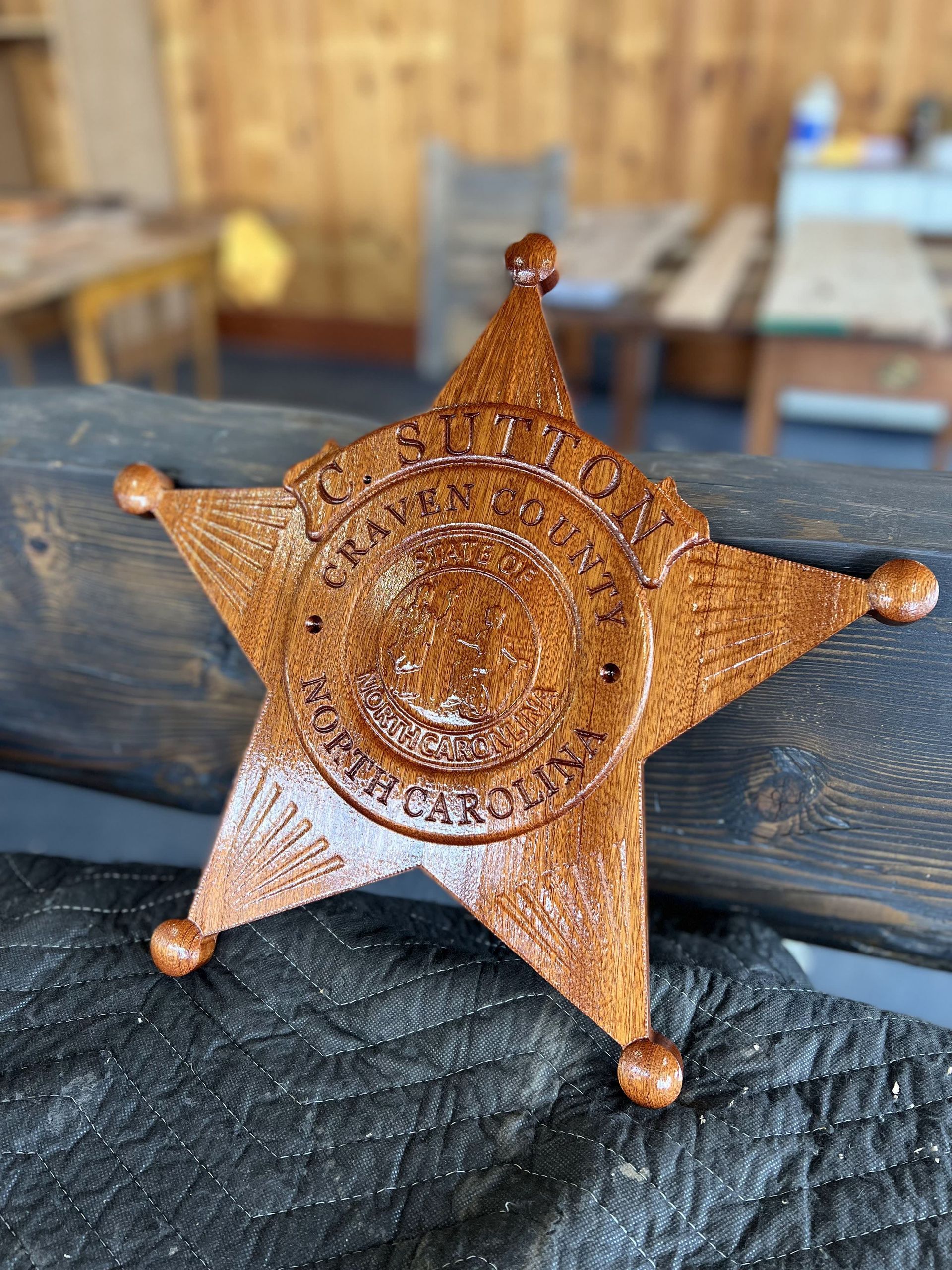A wooden sheriff 's badge is sitting on a wooden table.