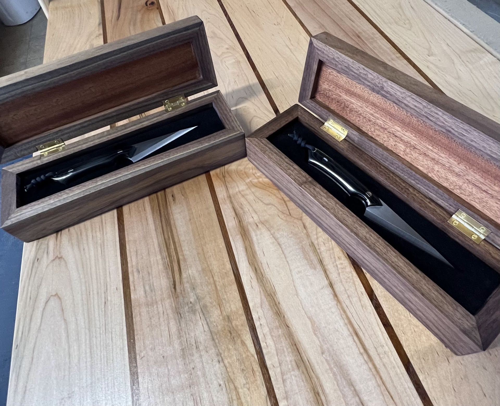 Two wooden boxes with a pen inside of them on a wooden table