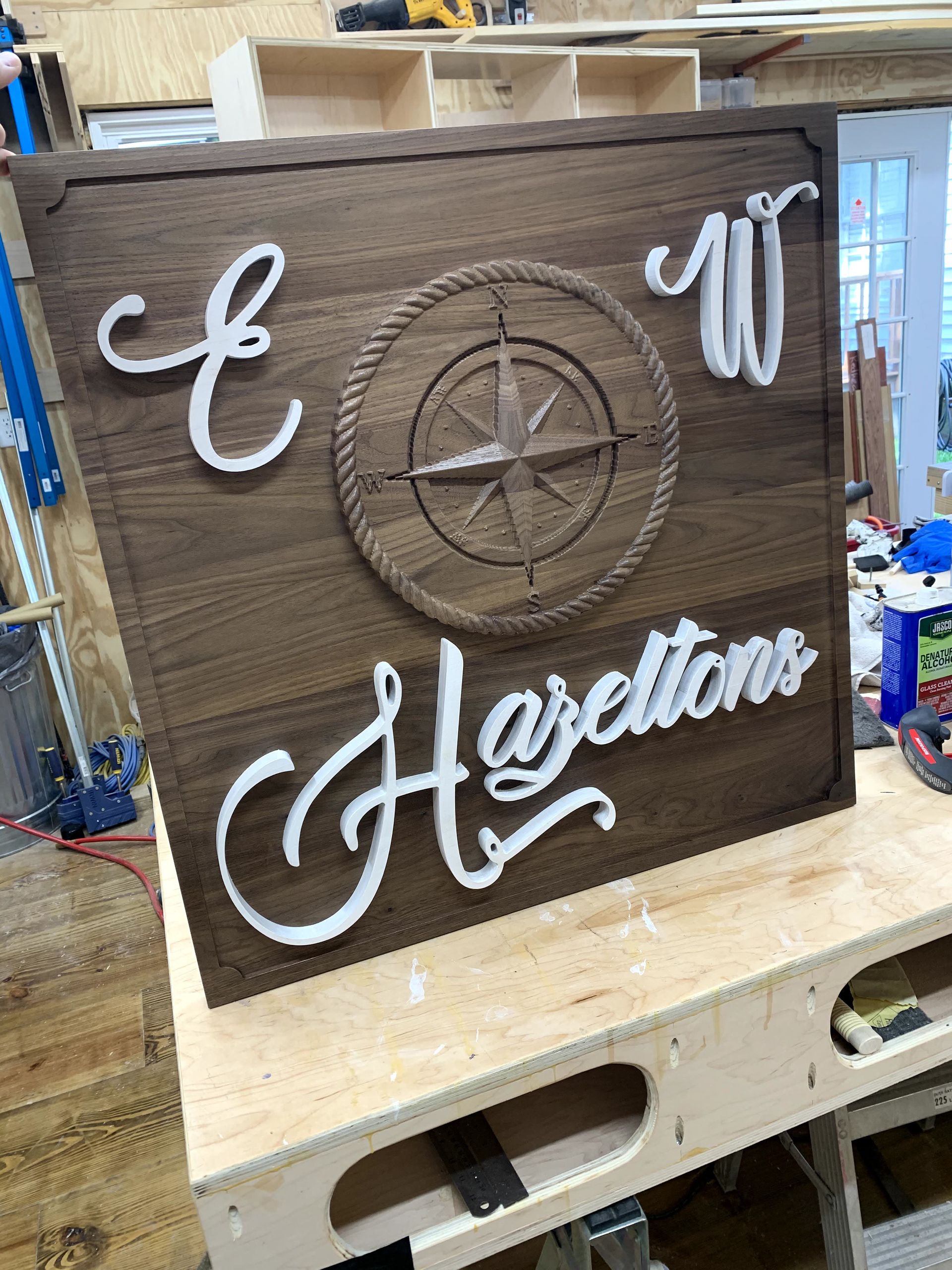 A wooden sign with a compass on it is sitting on top of a wooden table.