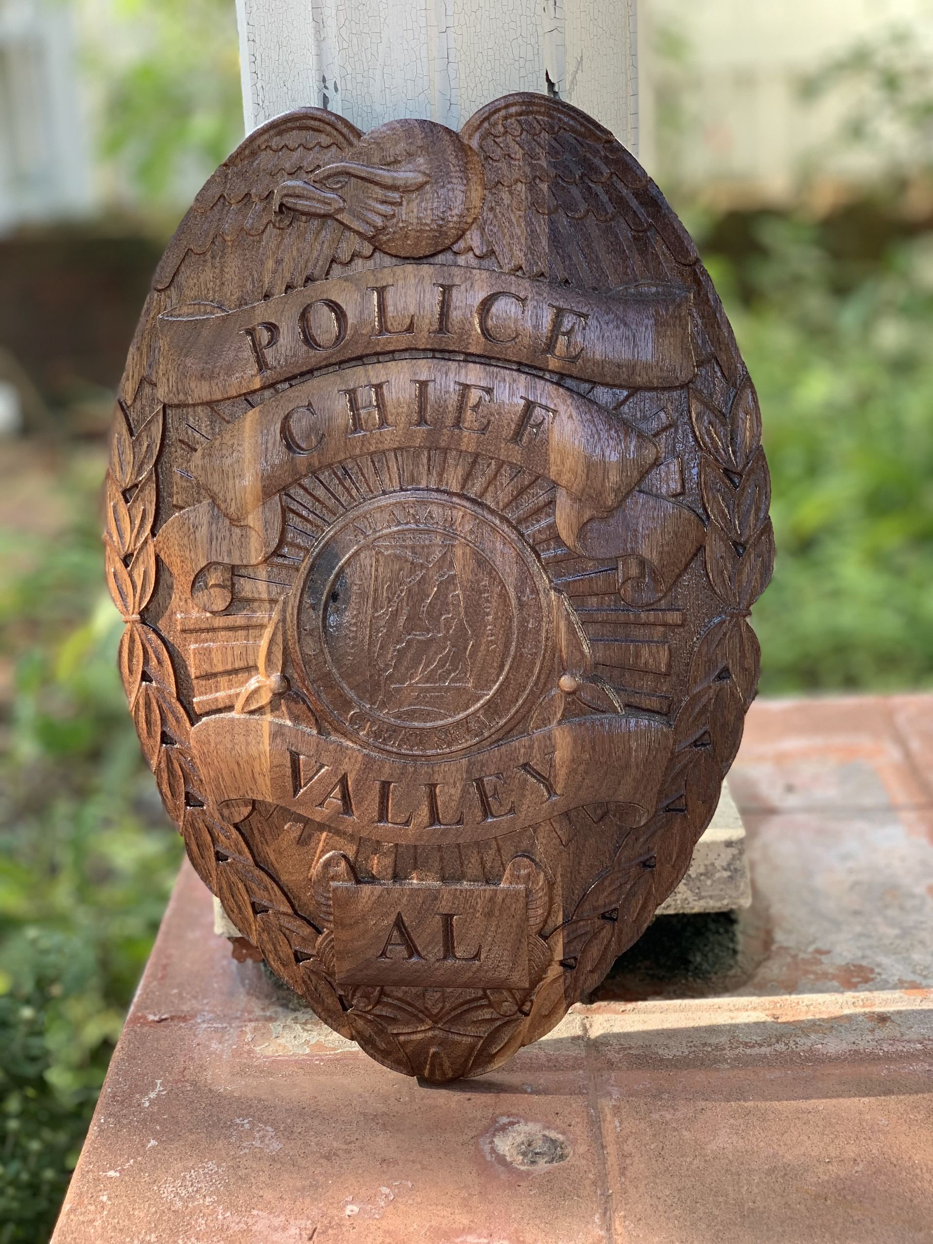 A wooden police badge is sitting on a brick wall.