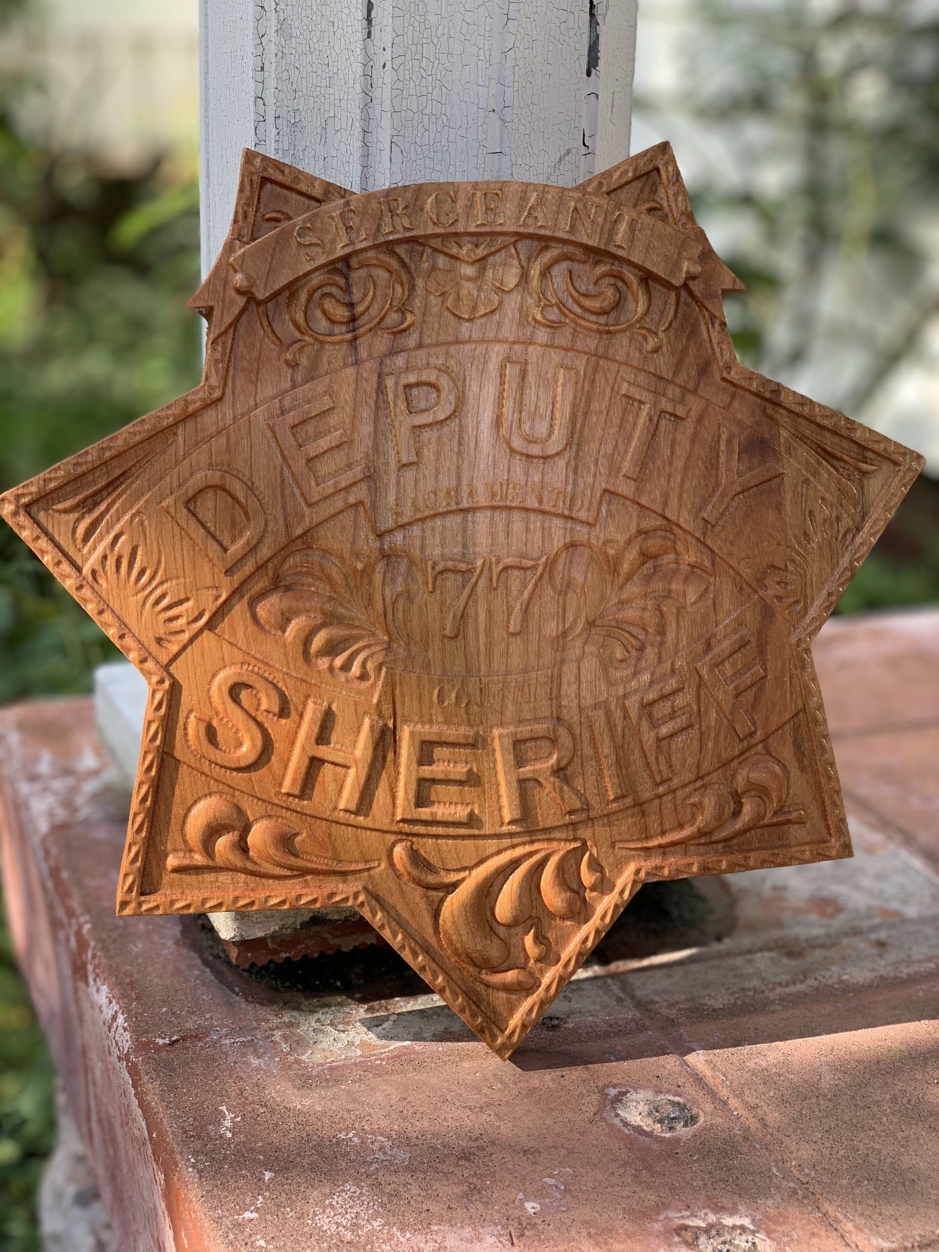 A wooden sheriff 's badge is sitting on top of a brick wall.