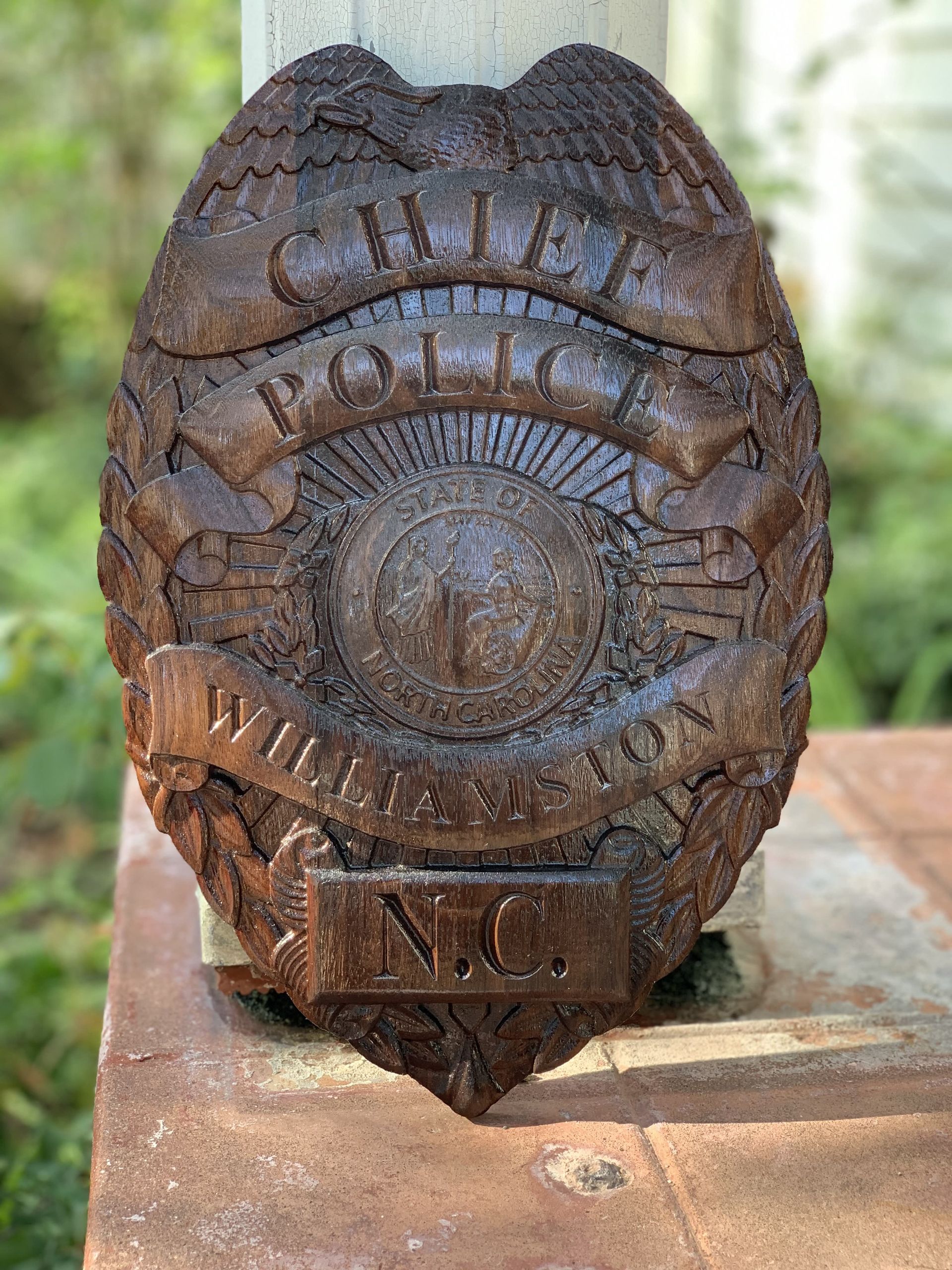 A wooden police badge is sitting on top of a brick wall.