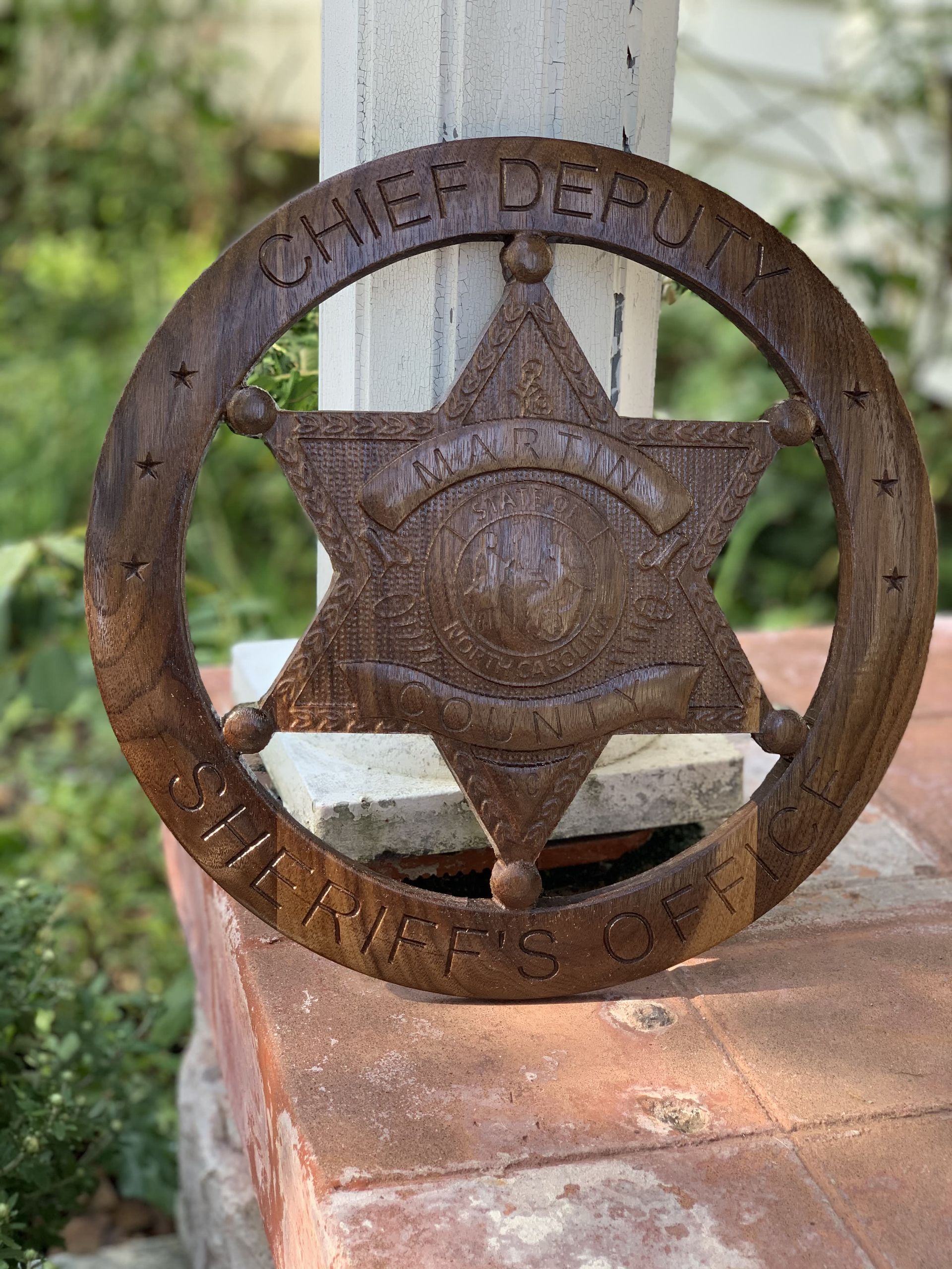 A rusty sheriff 's badge is sitting on a brick wall.