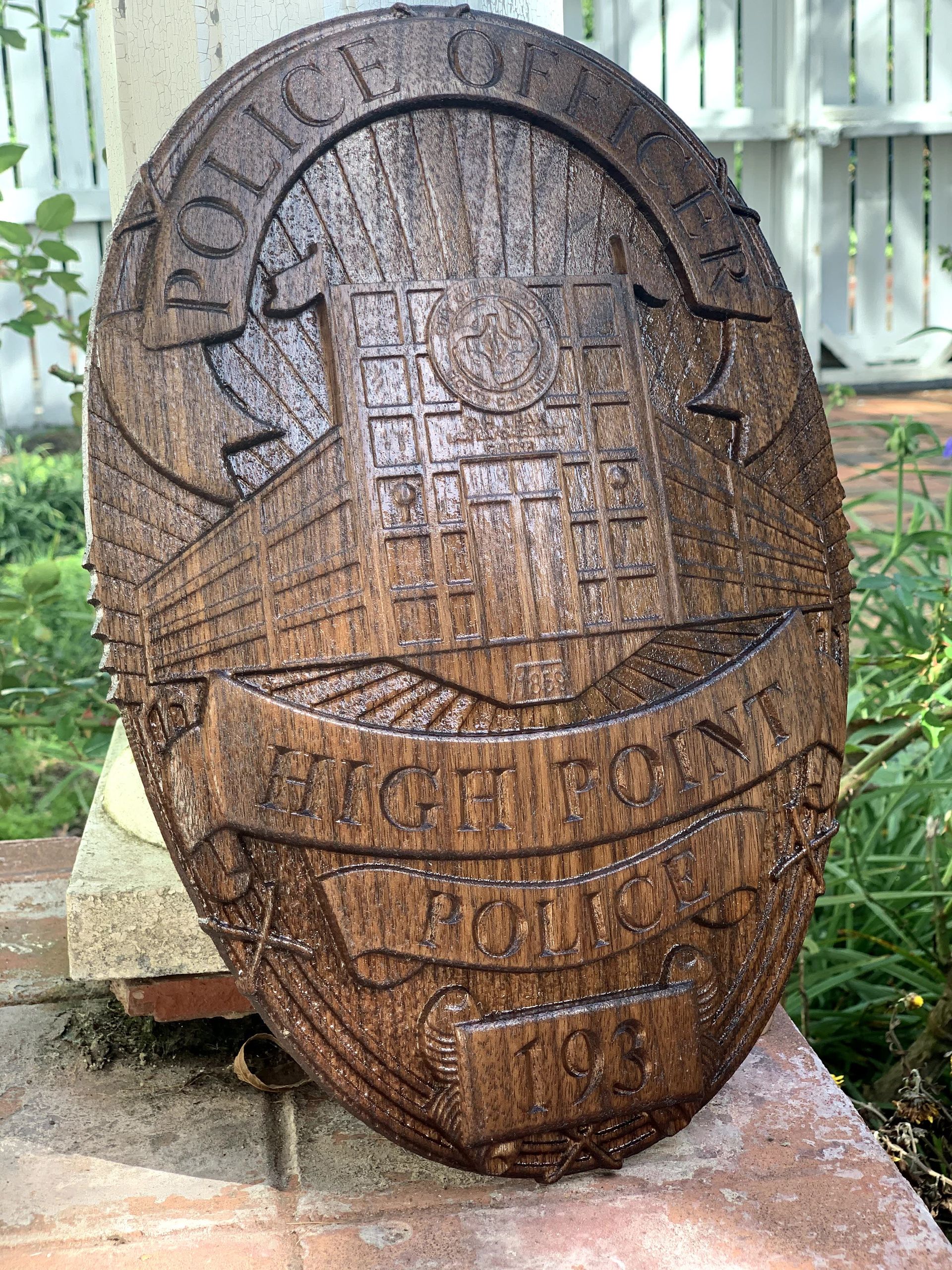 A wooden police badge is sitting on a brick wall.