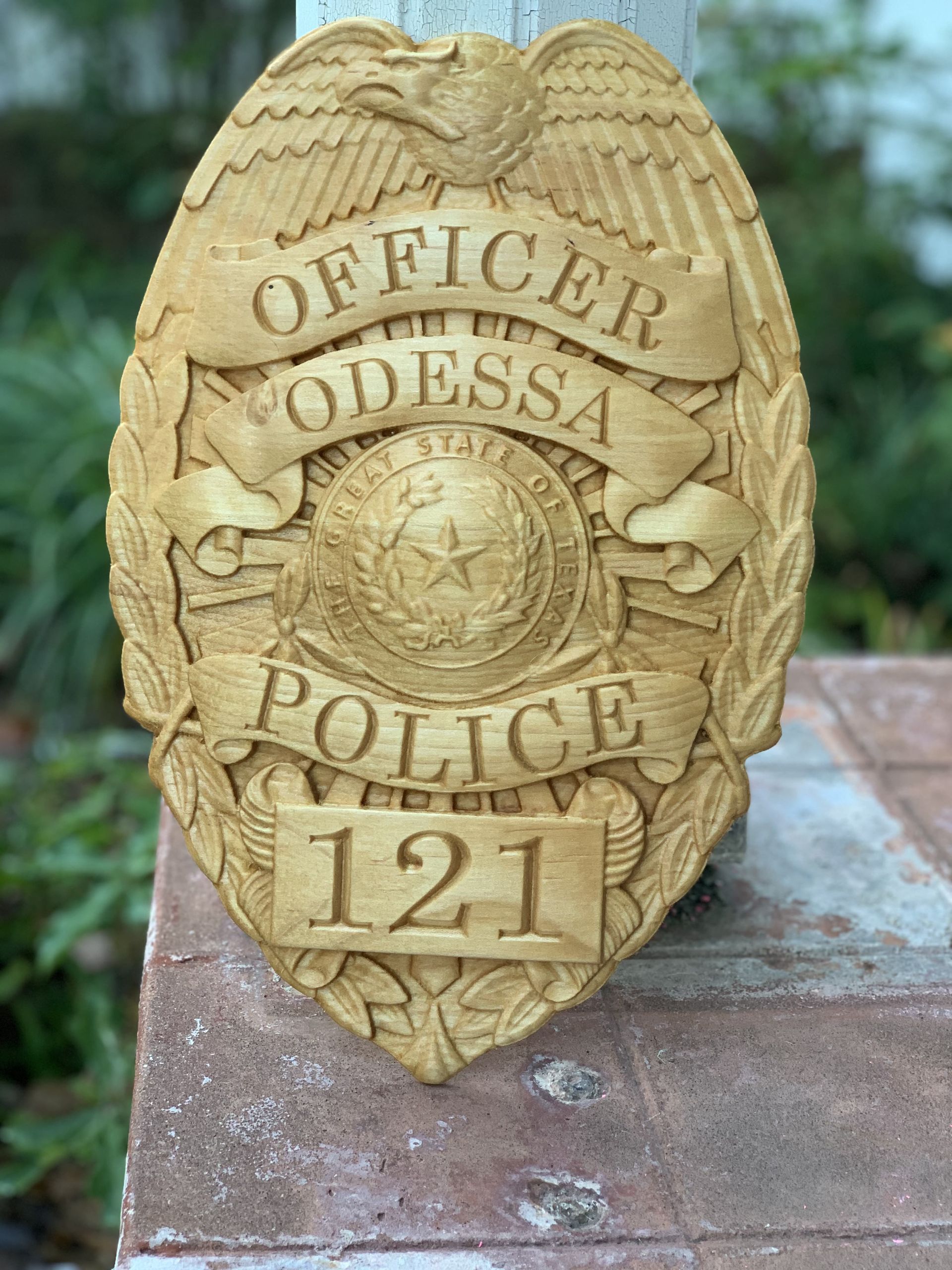 A wooden police badge is sitting on top of a brick wall.