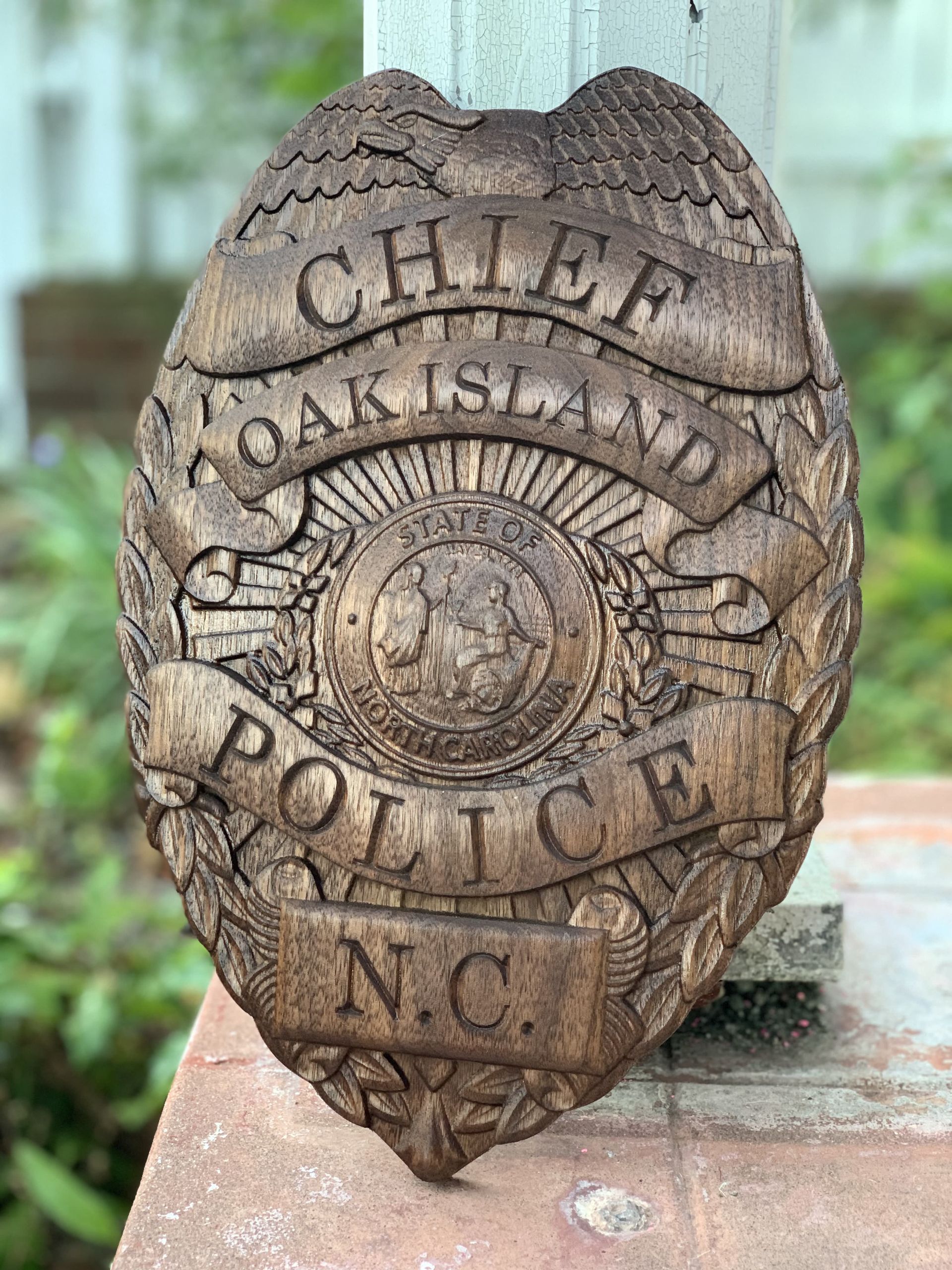A wooden police badge is sitting on a brick wall.