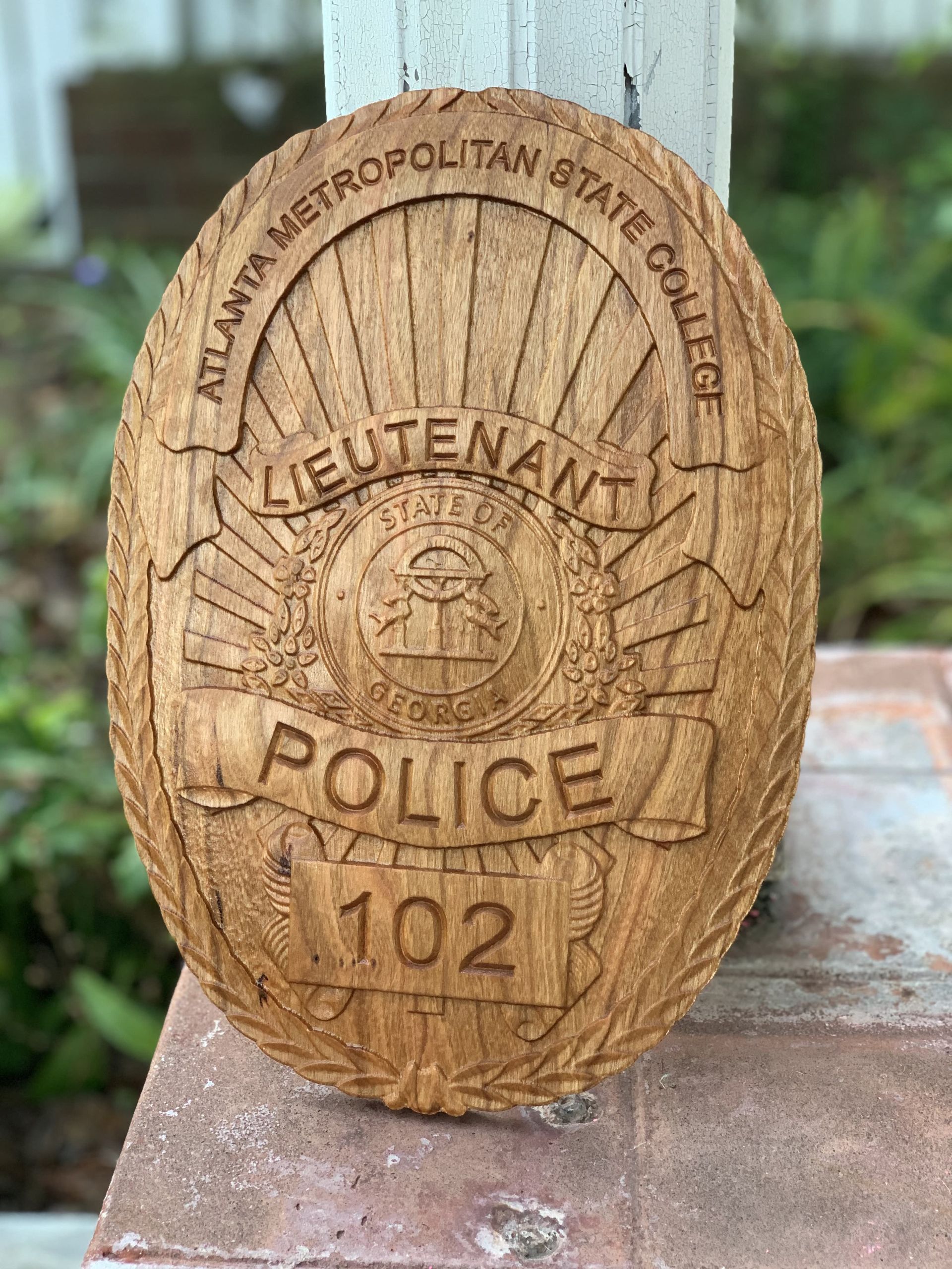 A wooden badge for a police lieutenant is sitting on a brick wall.