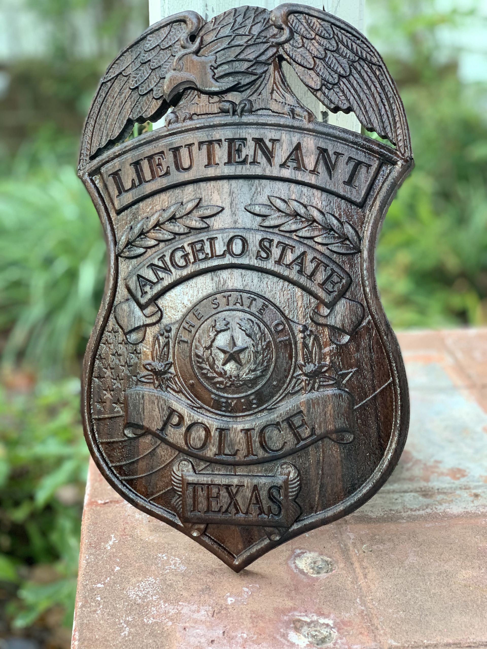 A wooden police badge is sitting on a brick wall.