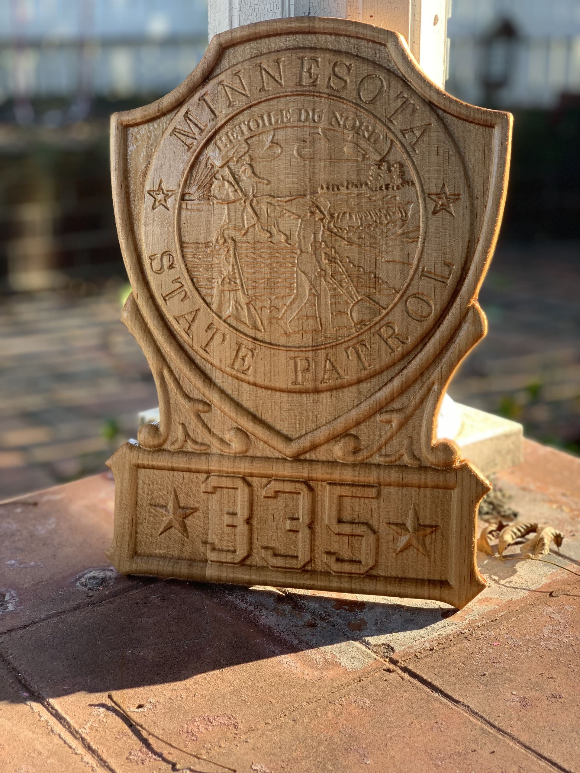 A wooden minnesota state patrol badge is sitting on a brick surface.