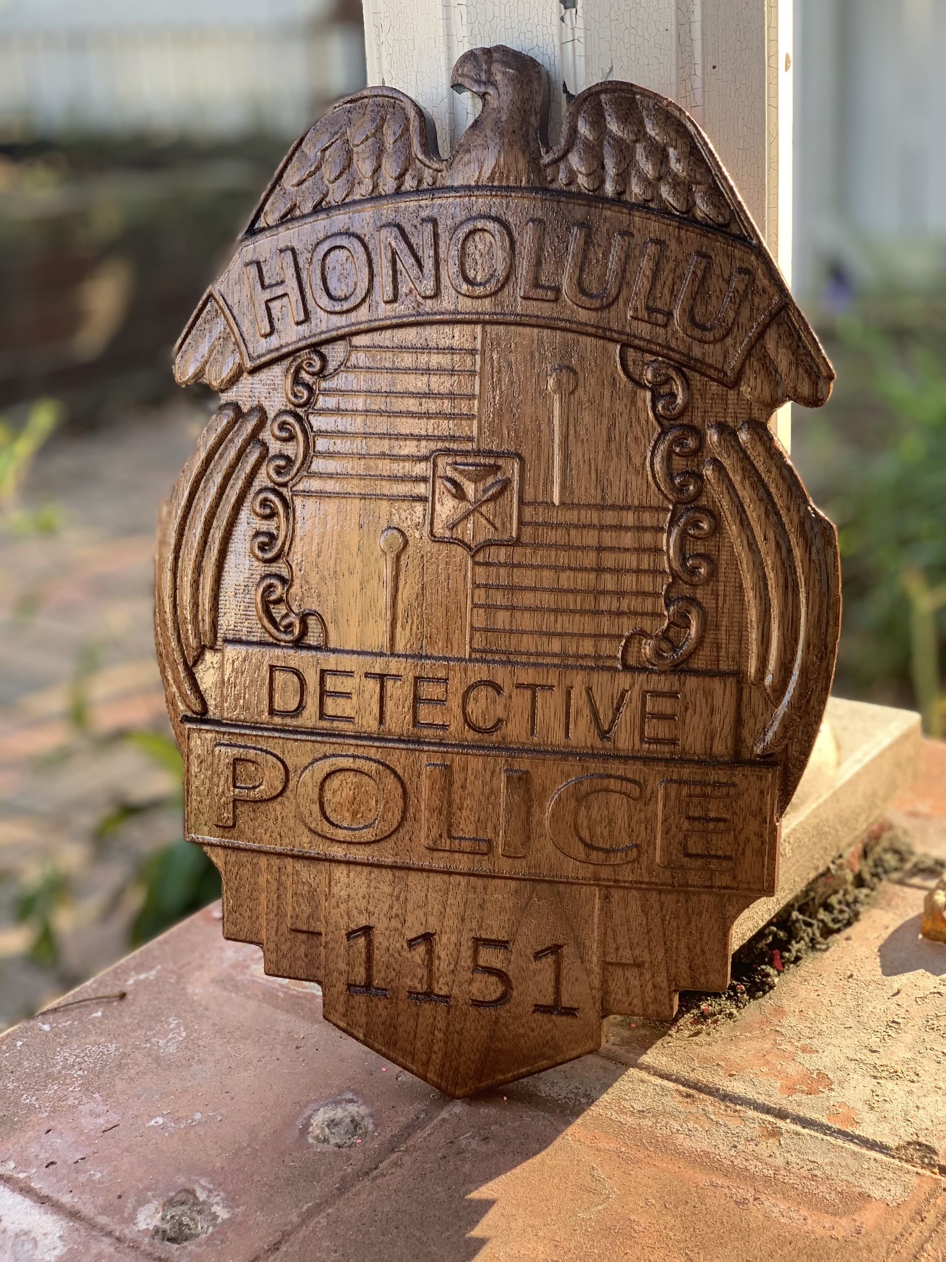 A wooden detective badge is sitting on a brick wall.