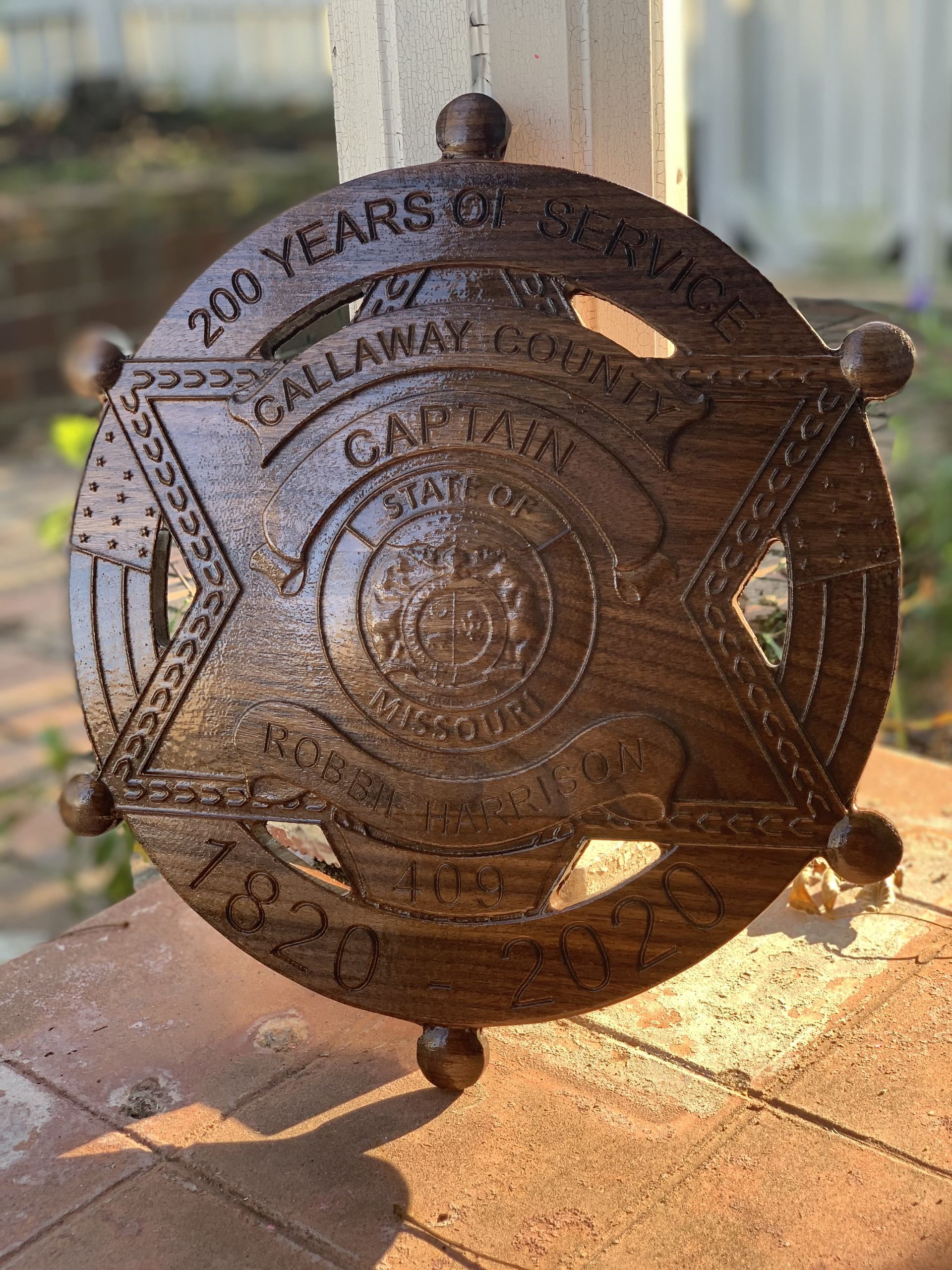 A wooden sheriff 's badge is sitting on a porch.