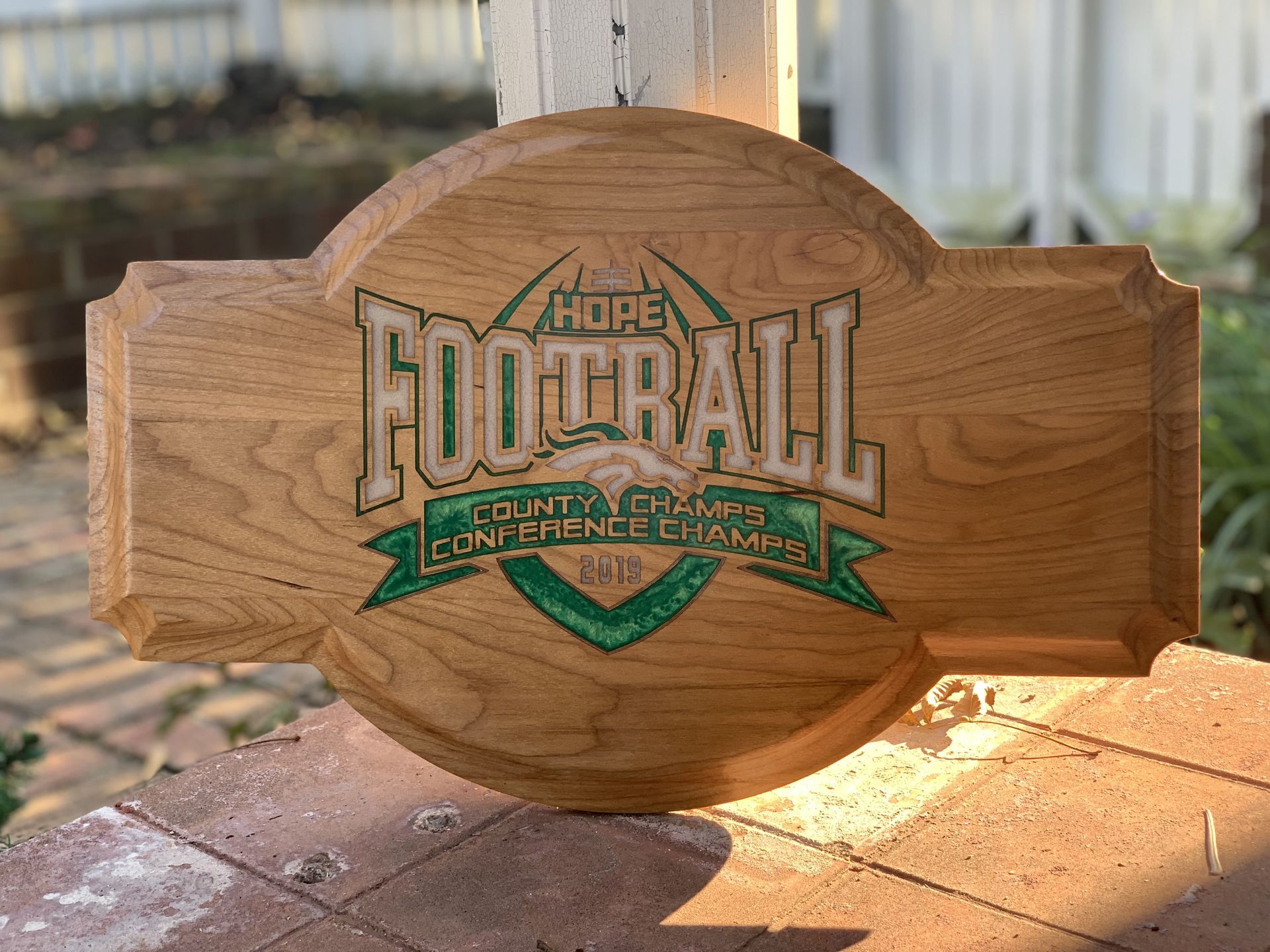 A wooden sign that says hope football is sitting on a brick wall.