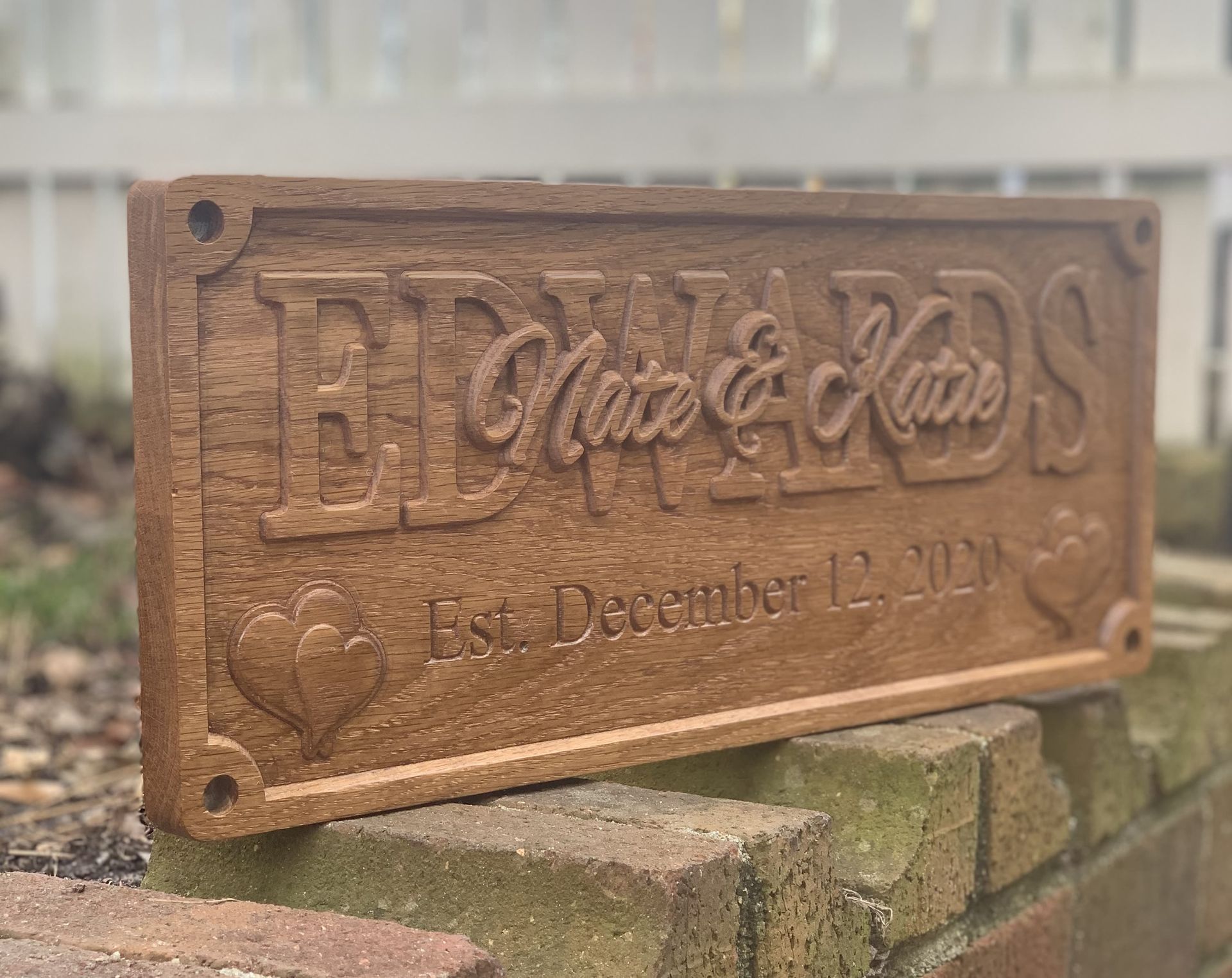 A wooden sign is sitting on top of a brick wall.