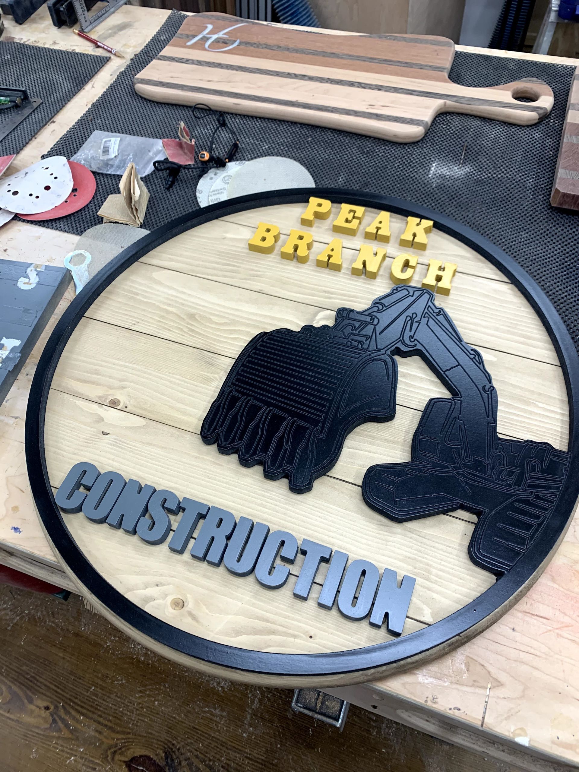 A wooden sign with an excavator on it is sitting on a wooden table.