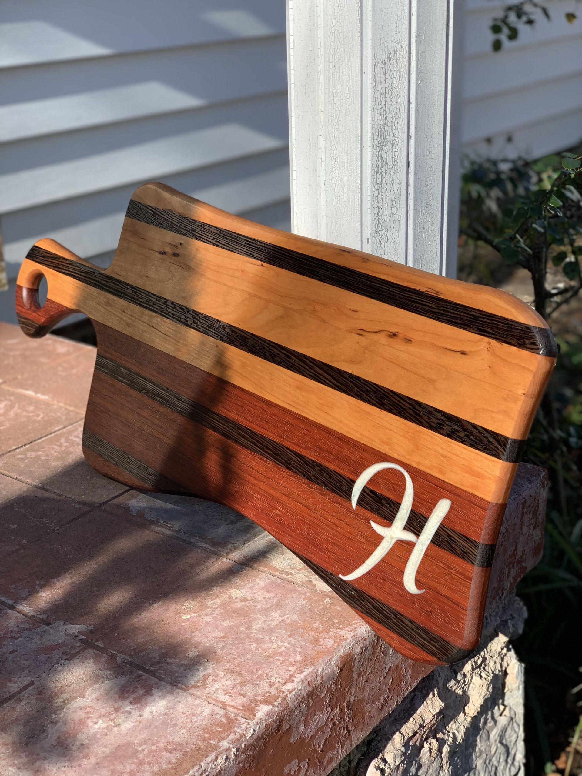 A wooden cutting board with the letter h on it