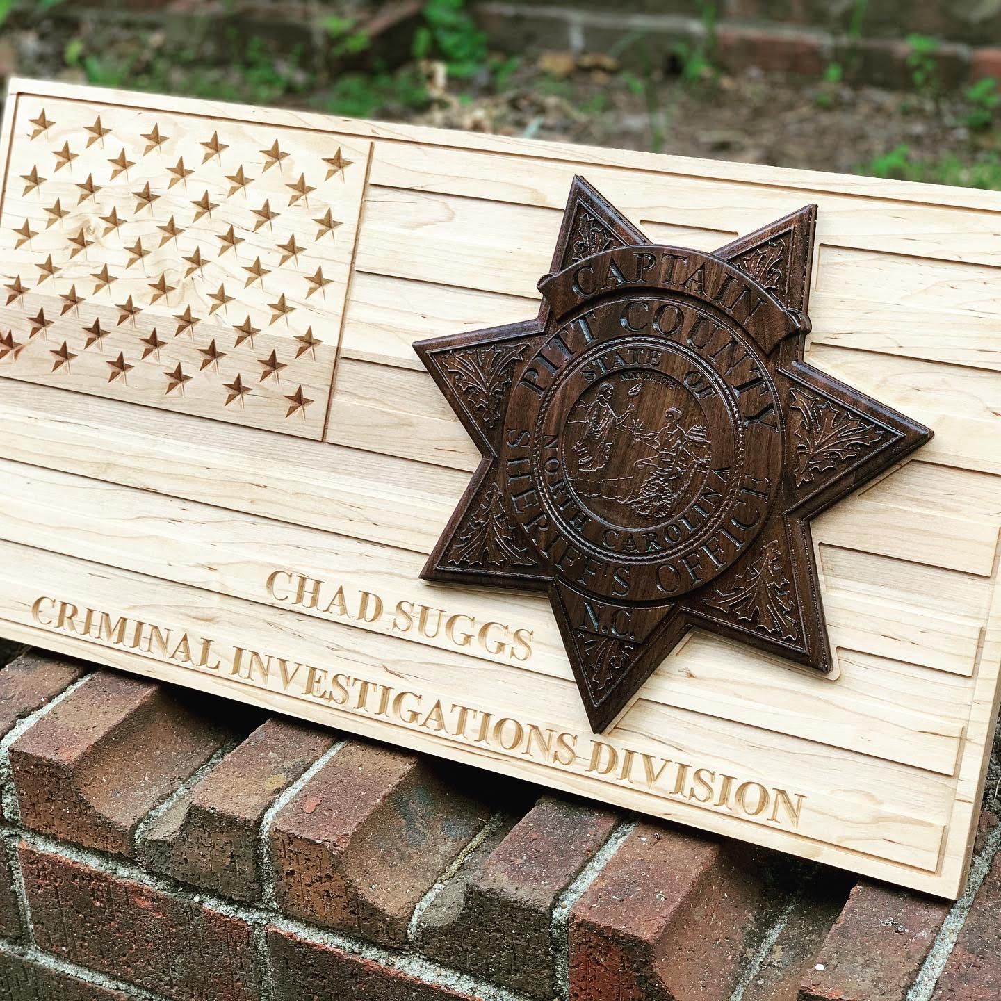 A wooden sign with a police badge on it is sitting on top of a brick wall.