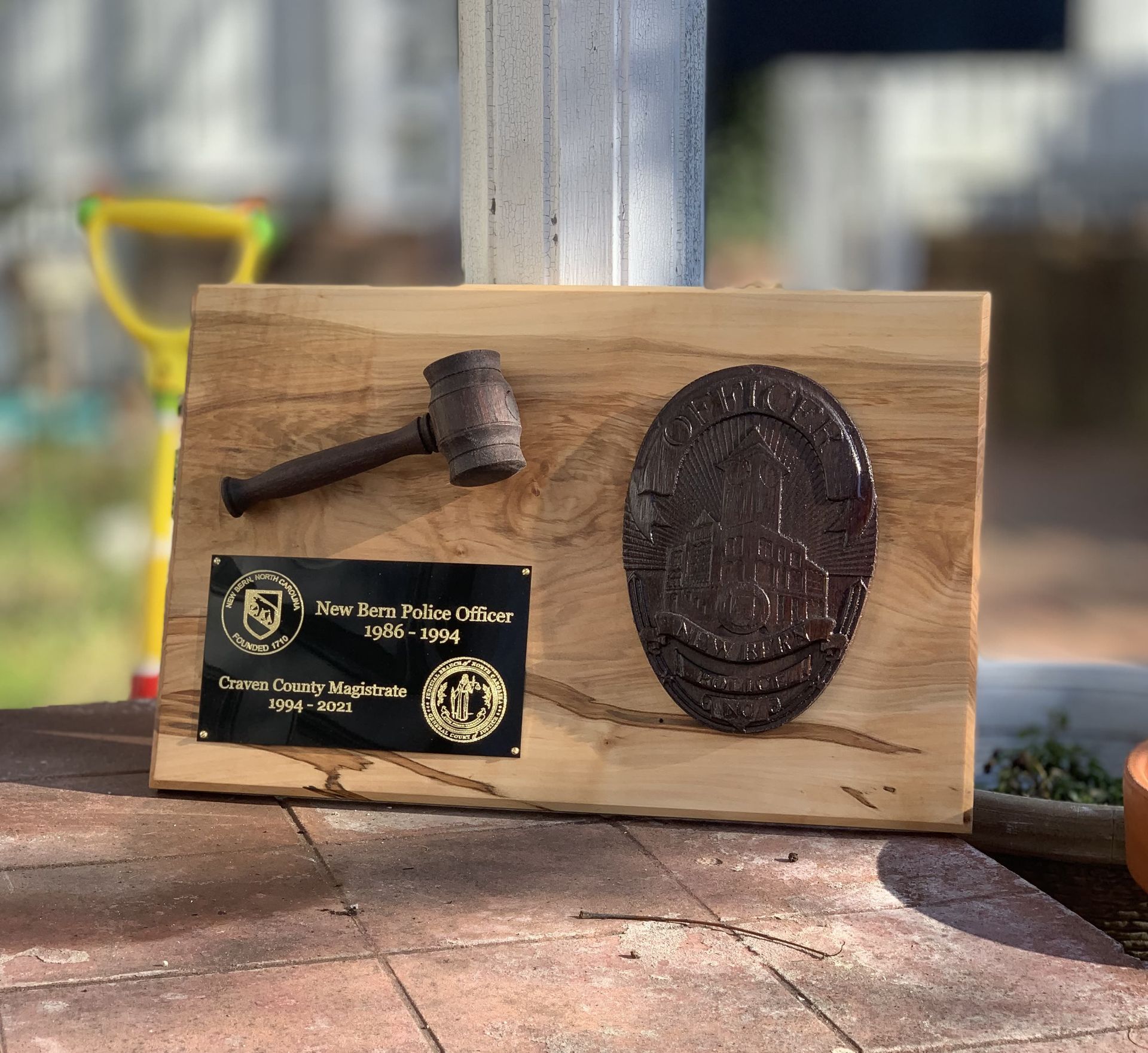 A wooden plaque with a hammer and a coin on it