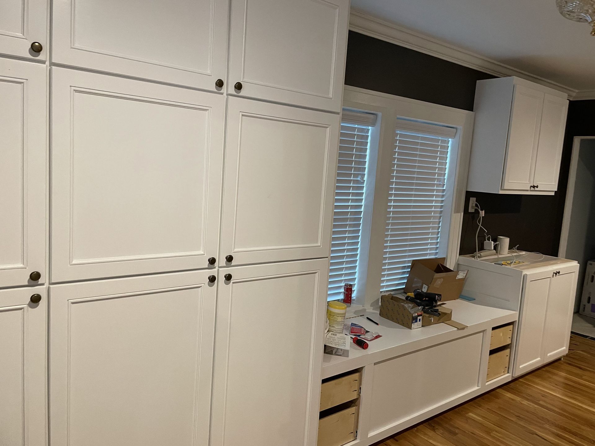 A kitchen with white cabinets , a sink , and a window.