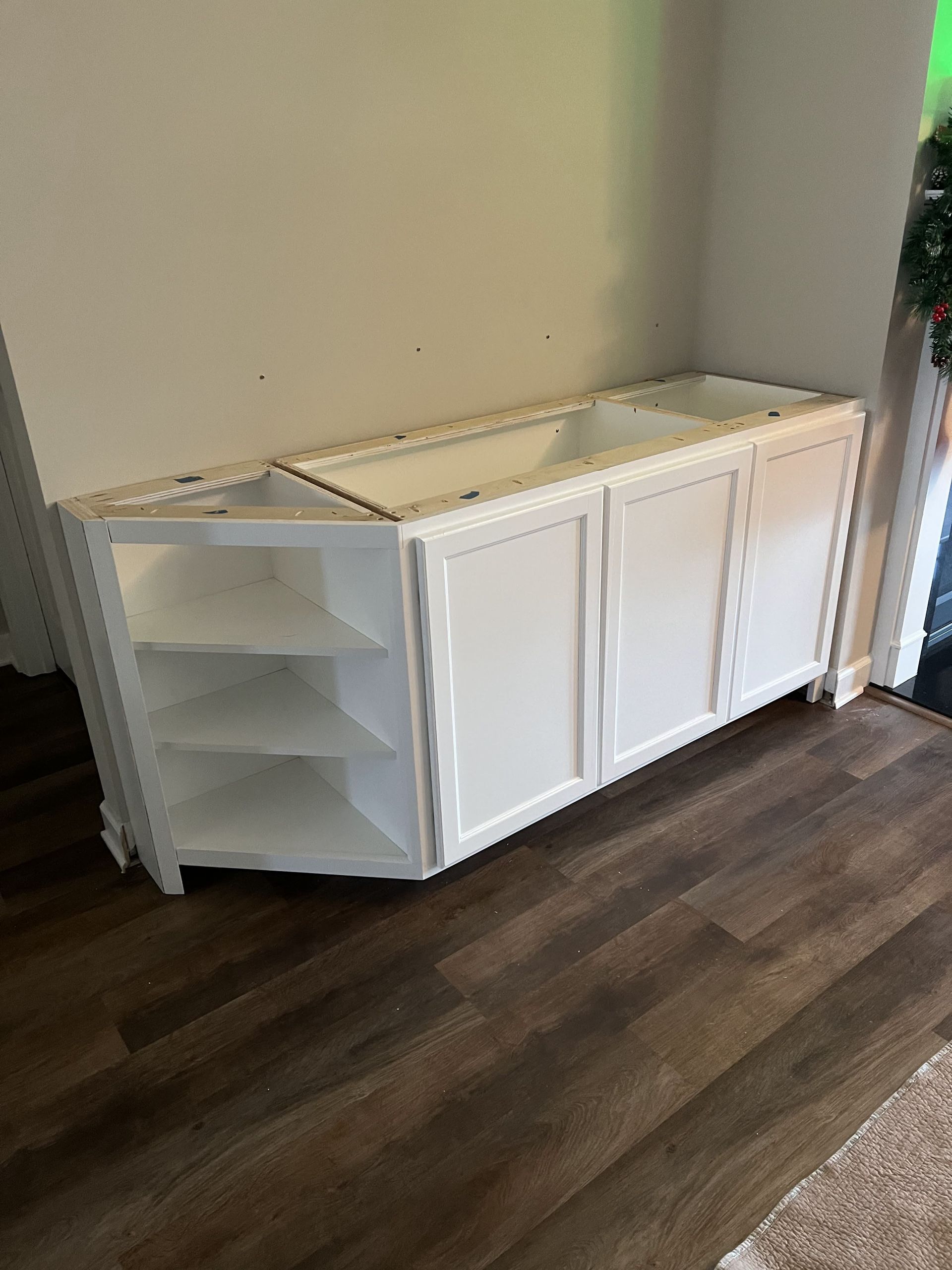 A white cabinet is sitting on a wooden floor in a room.