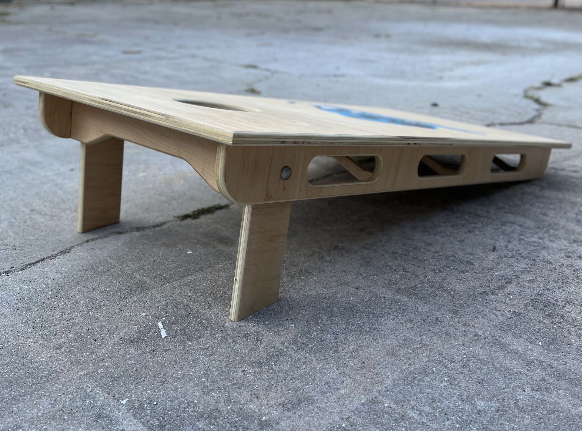 A wooden cornhole board is sitting on the ground.