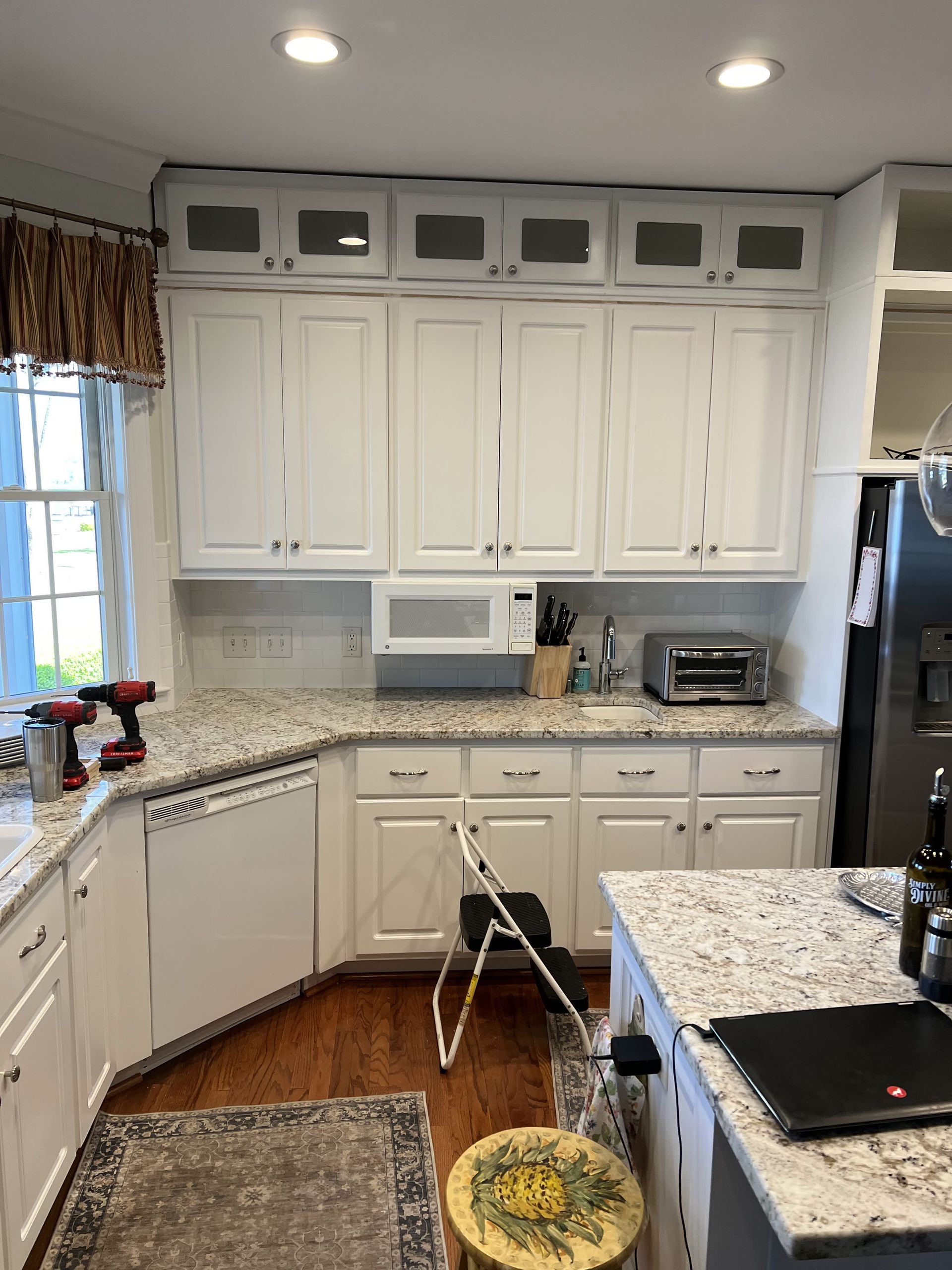 A kitchen with white cabinets and granite counter tops.