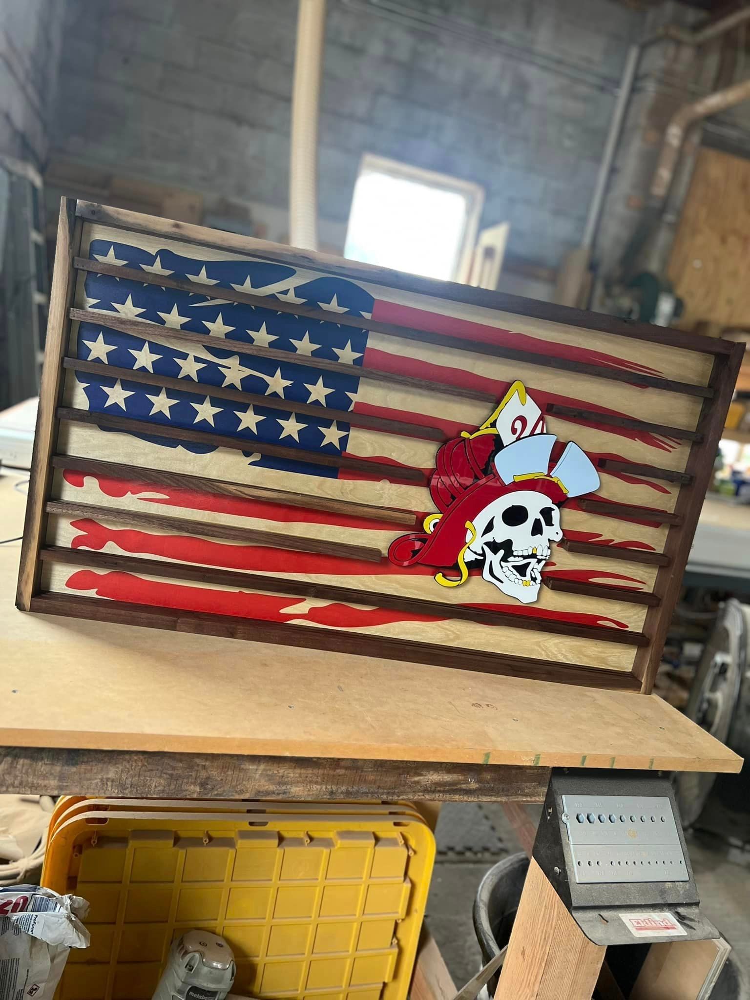 A wooden american flag with a skull on it is sitting on top of a wooden table.