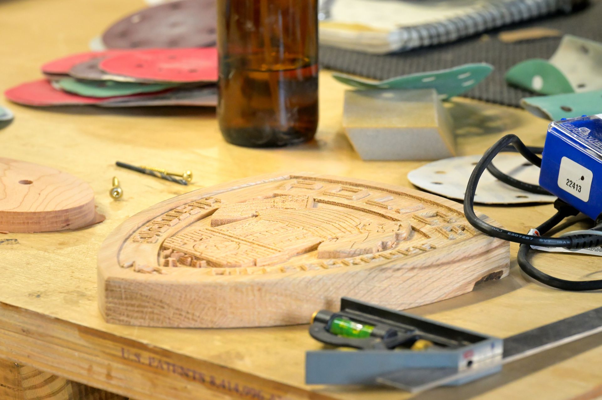 A piece of wood is sitting on a wooden table next to a bottle of beer.