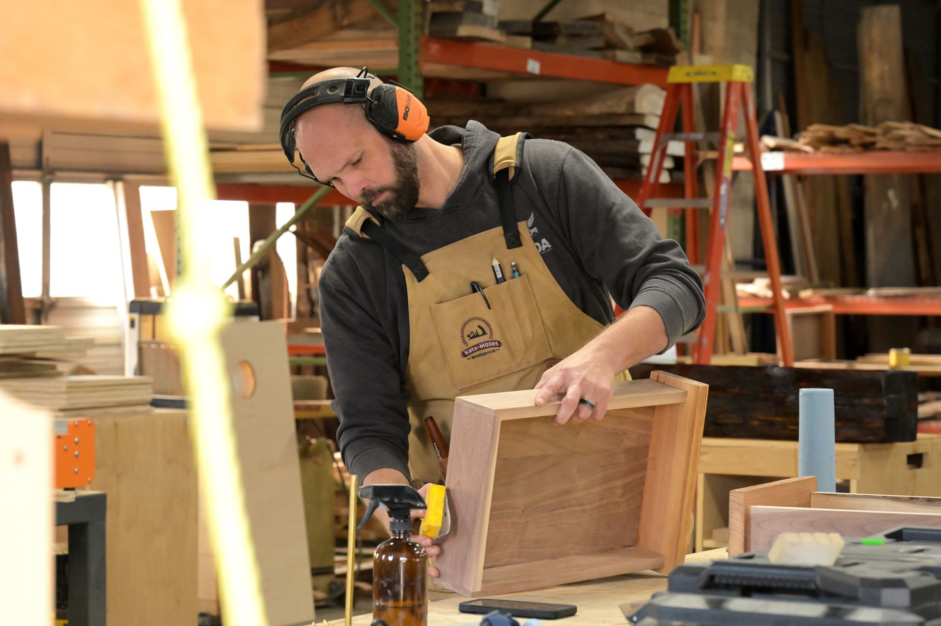 A man wearing headphones is working on a piece of wood.