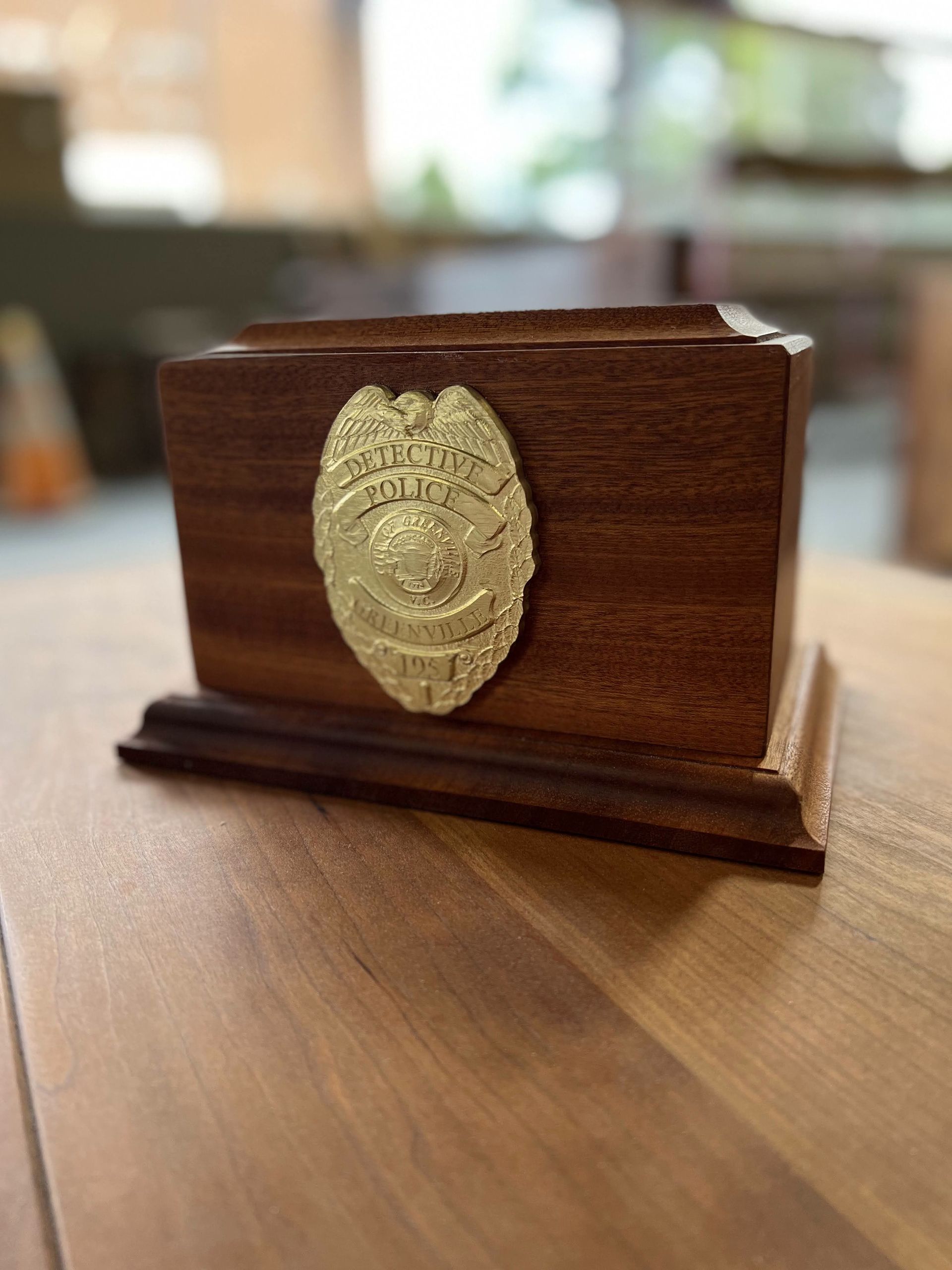 A wooden box with a gold badge on it is sitting on a wooden table.