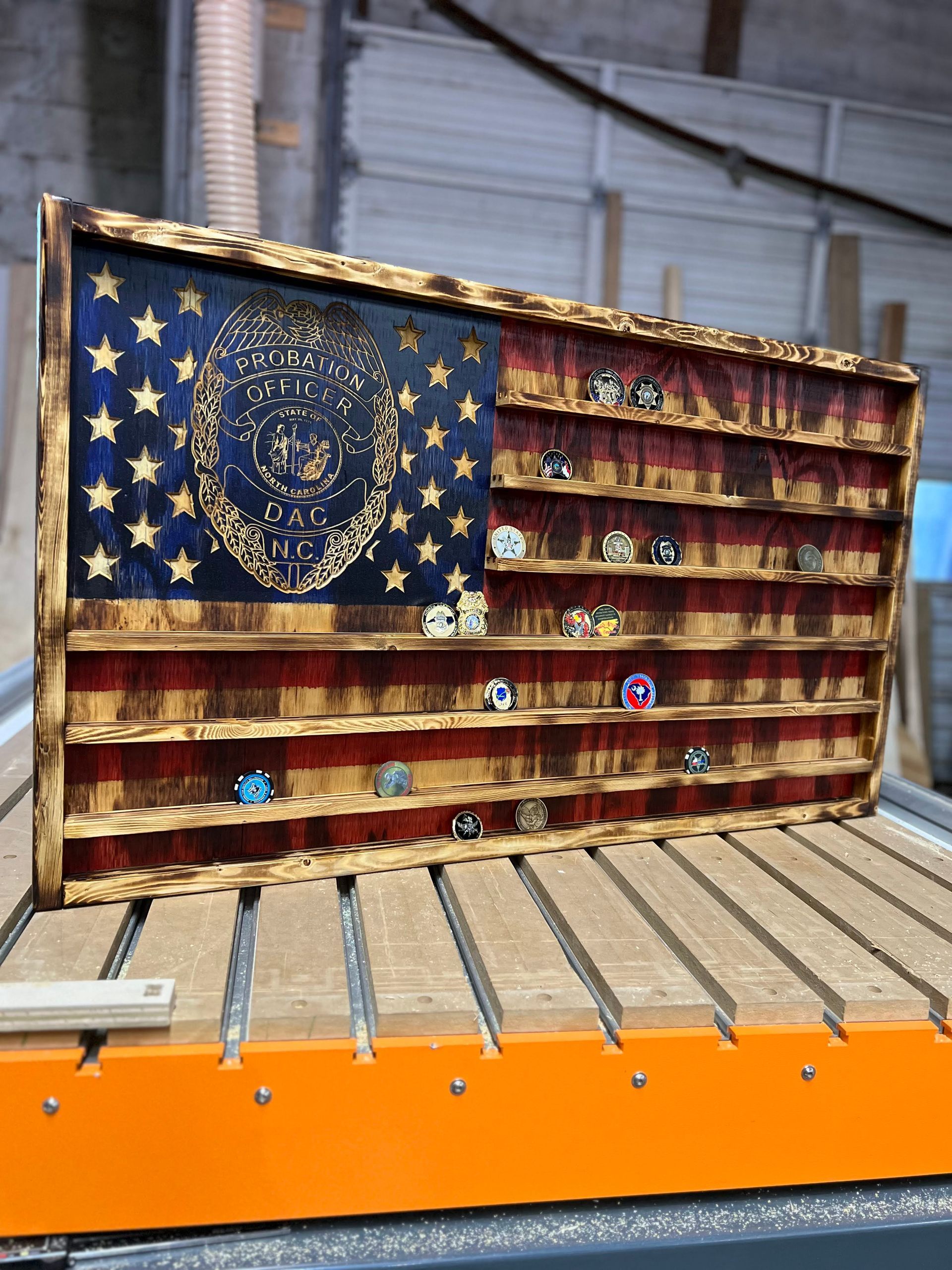 A wooden american flag with a lion on it is sitting on top of a wooden table.