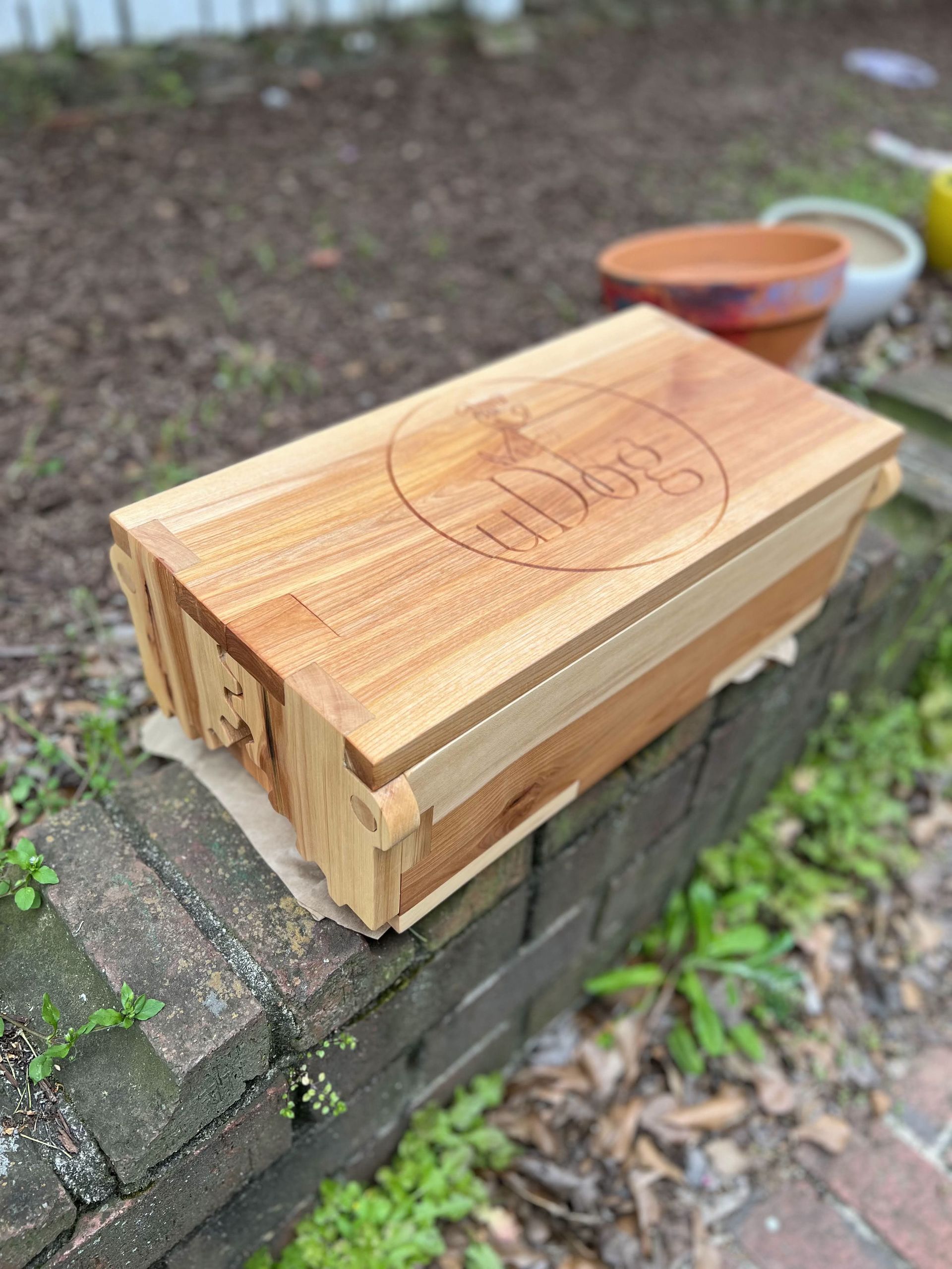A wooden box is sitting on top of a brick wall.