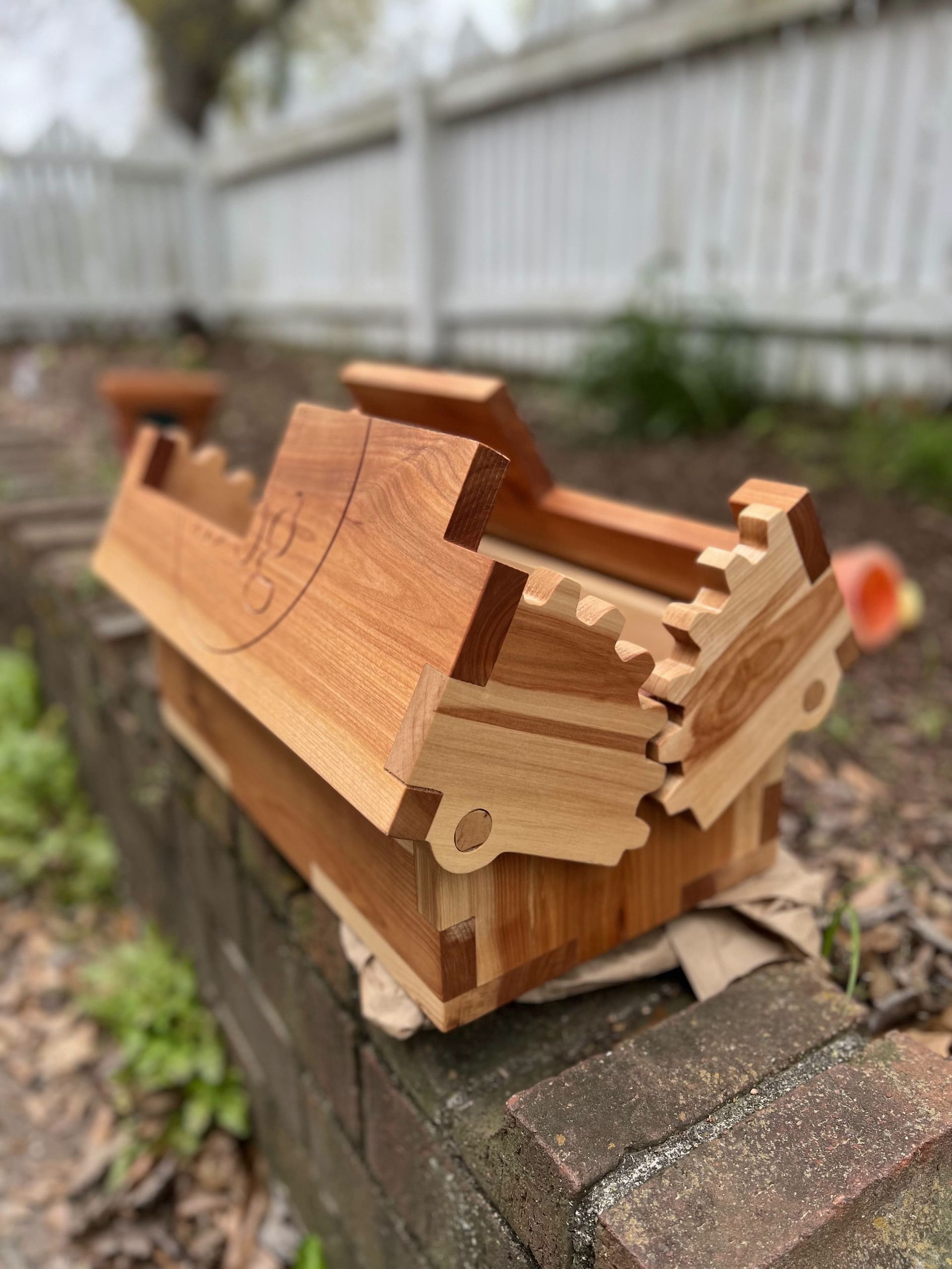 A wooden box is sitting on top of a brick wall.