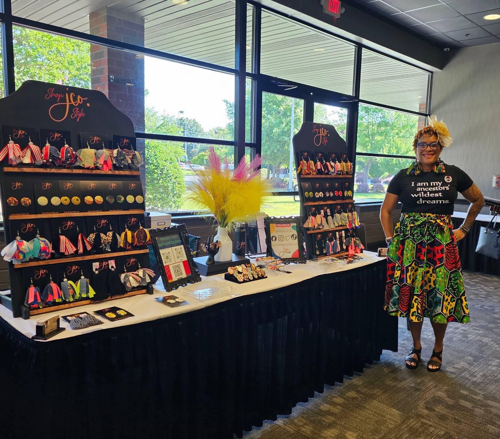 A woman is standing in front of a table with a lot of jewelry on it.