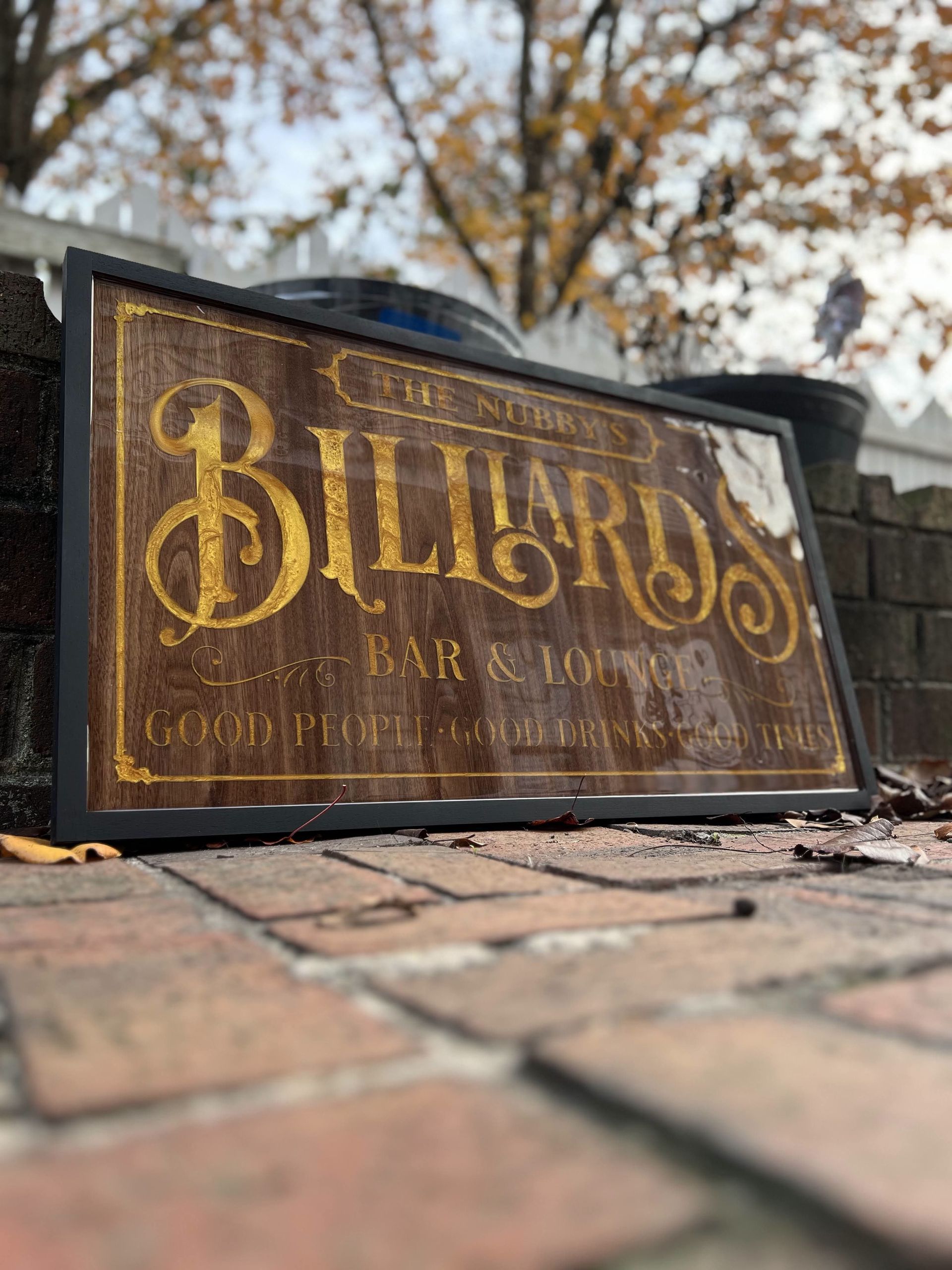 A billiards sign is sitting on a brick sidewalk.