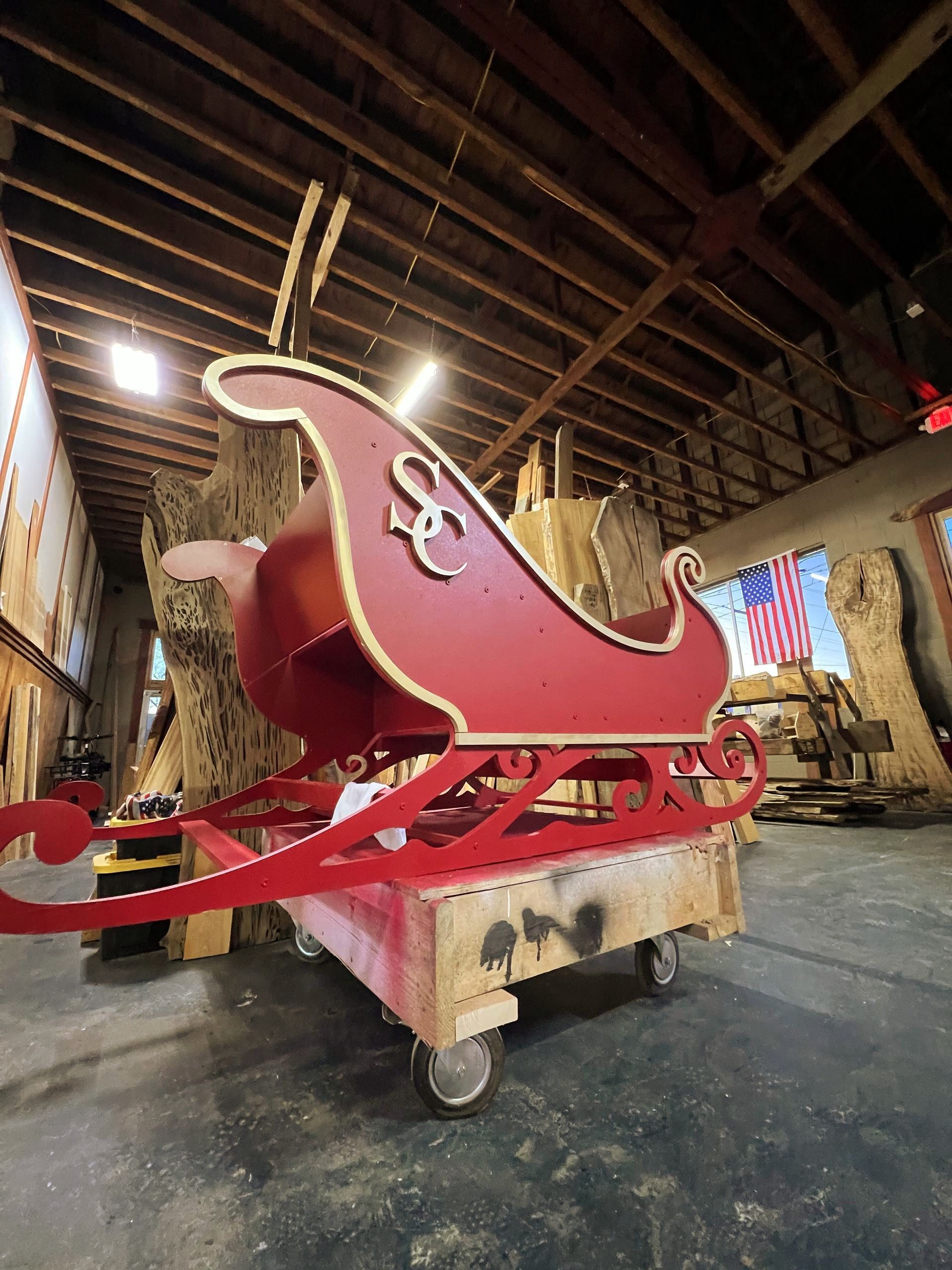 A large red sleigh is sitting on a cart in a room.
